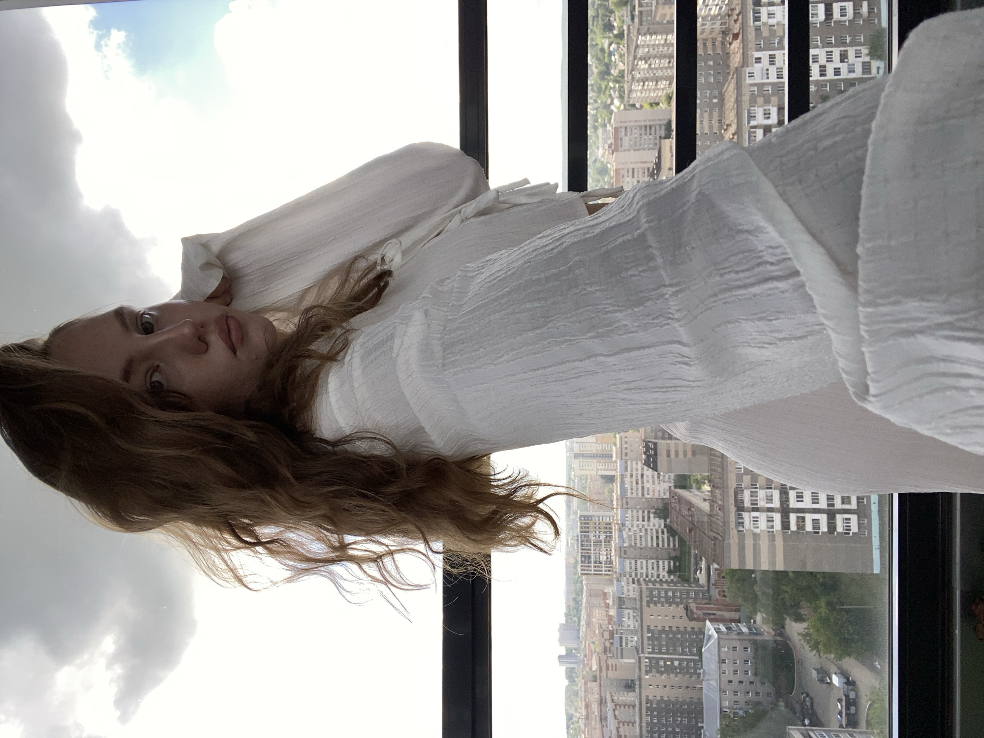 Woman photographed by window overlooking Izhevsk cityscape