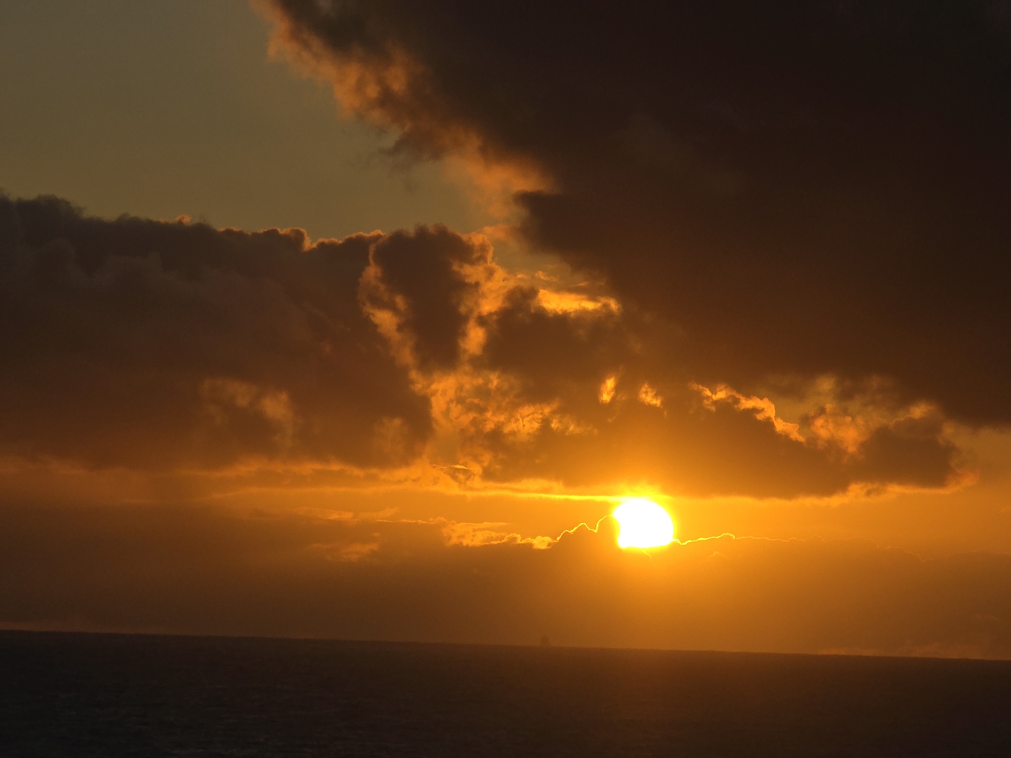 Orange sunset pierces dark clouds over Norwegian coastline