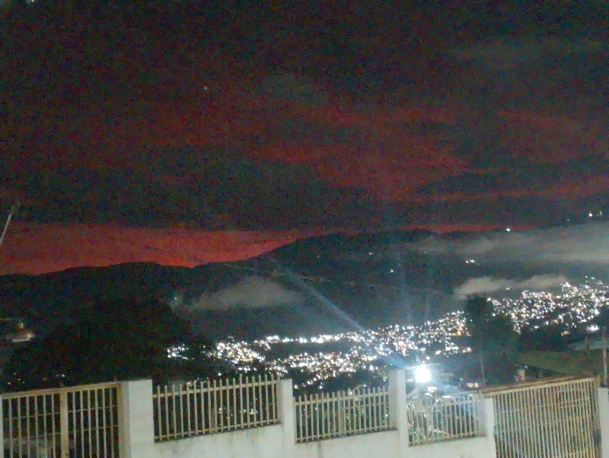 Nighttime view captures Caracas cityscape through fog-covered hills