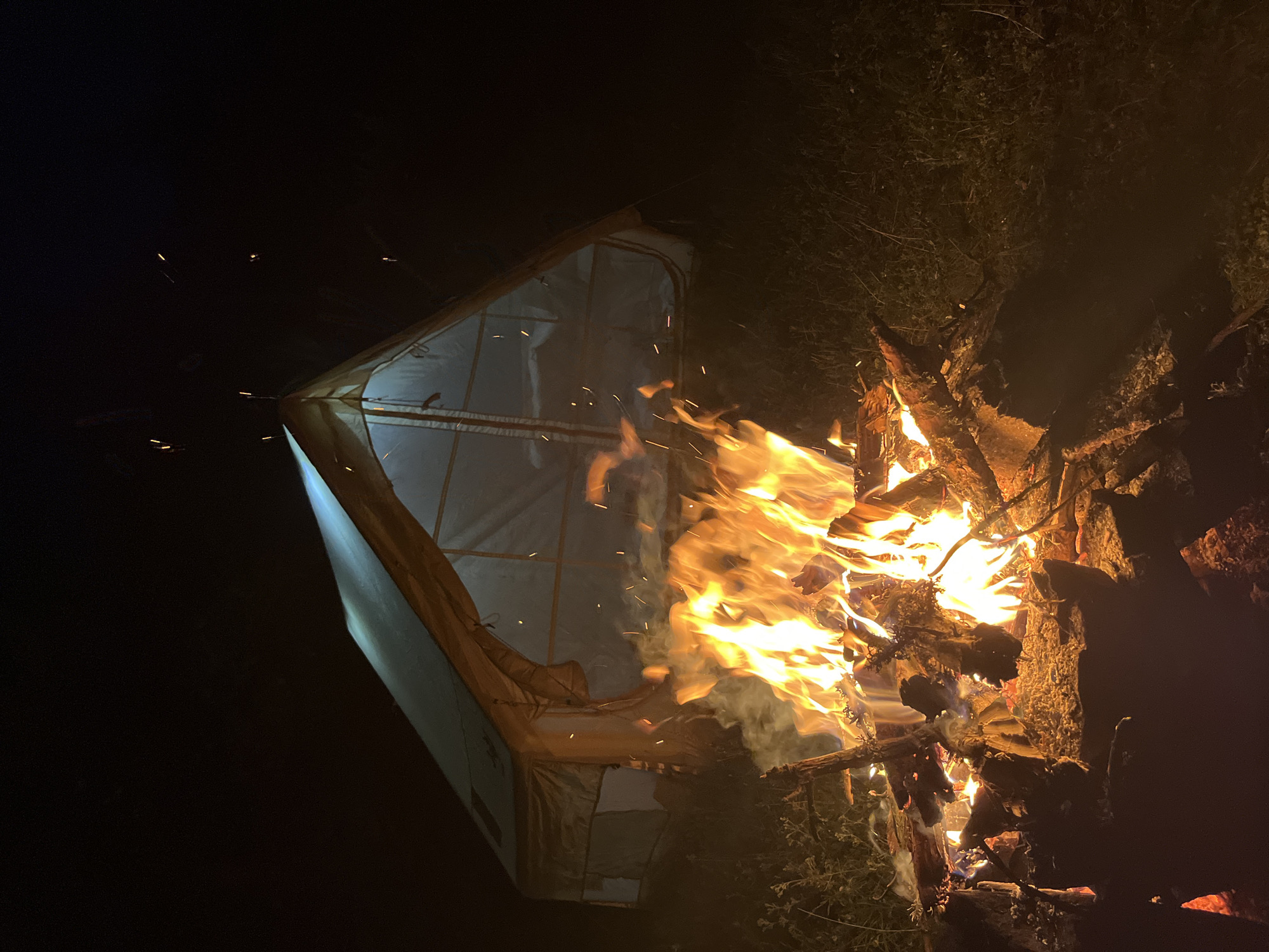 Campfire and tent under a full moon in rural Bulgaria
