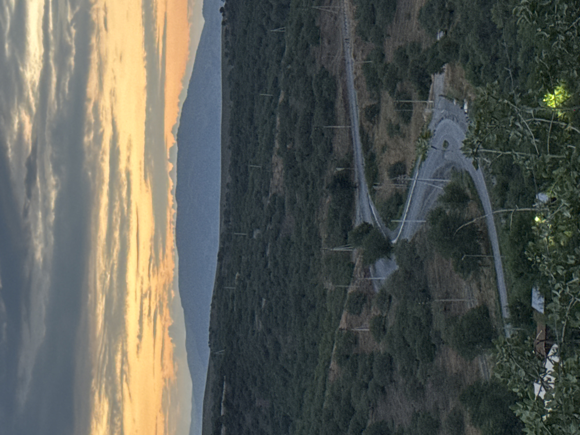 Manas at dusk: hillside roads, flags, and city lights at night