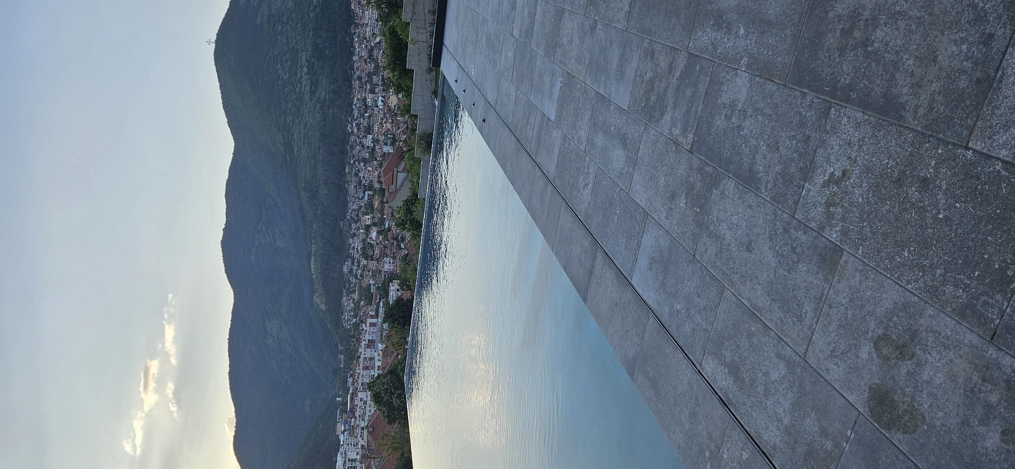 Hillside town with cross-topped mountain observed from multiple angles