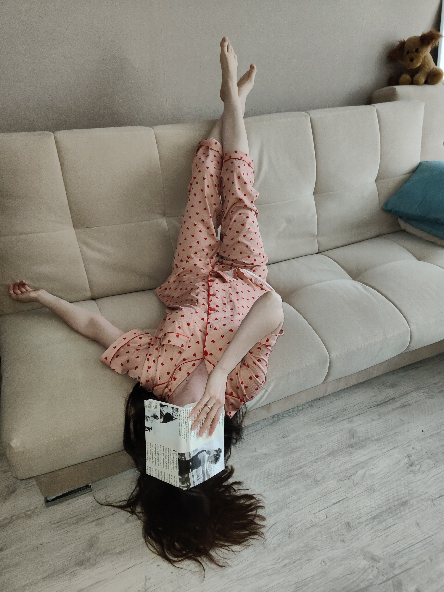 Person lounges in pajamas on sofa, reads newspaper