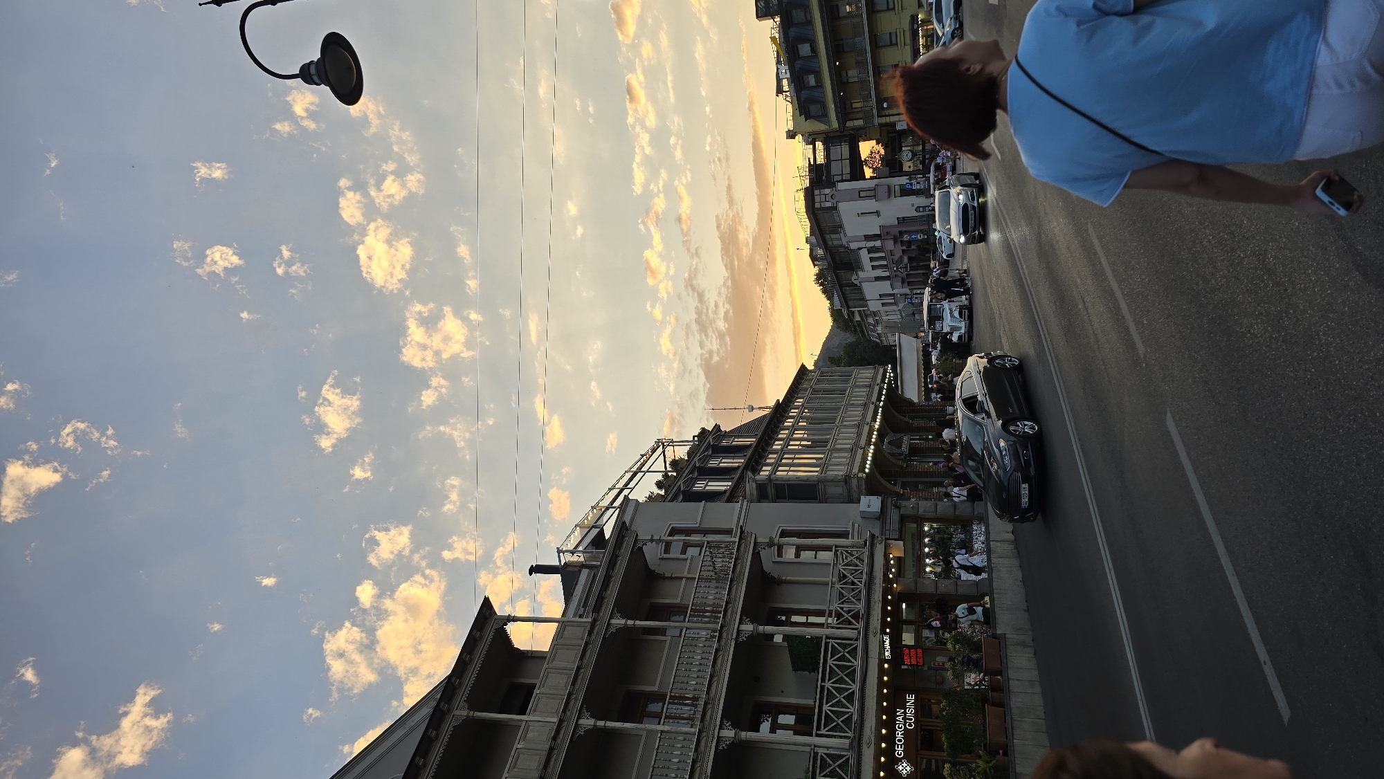 Tbilisi street at dusk: juice stand, restaurant sign, fading sky