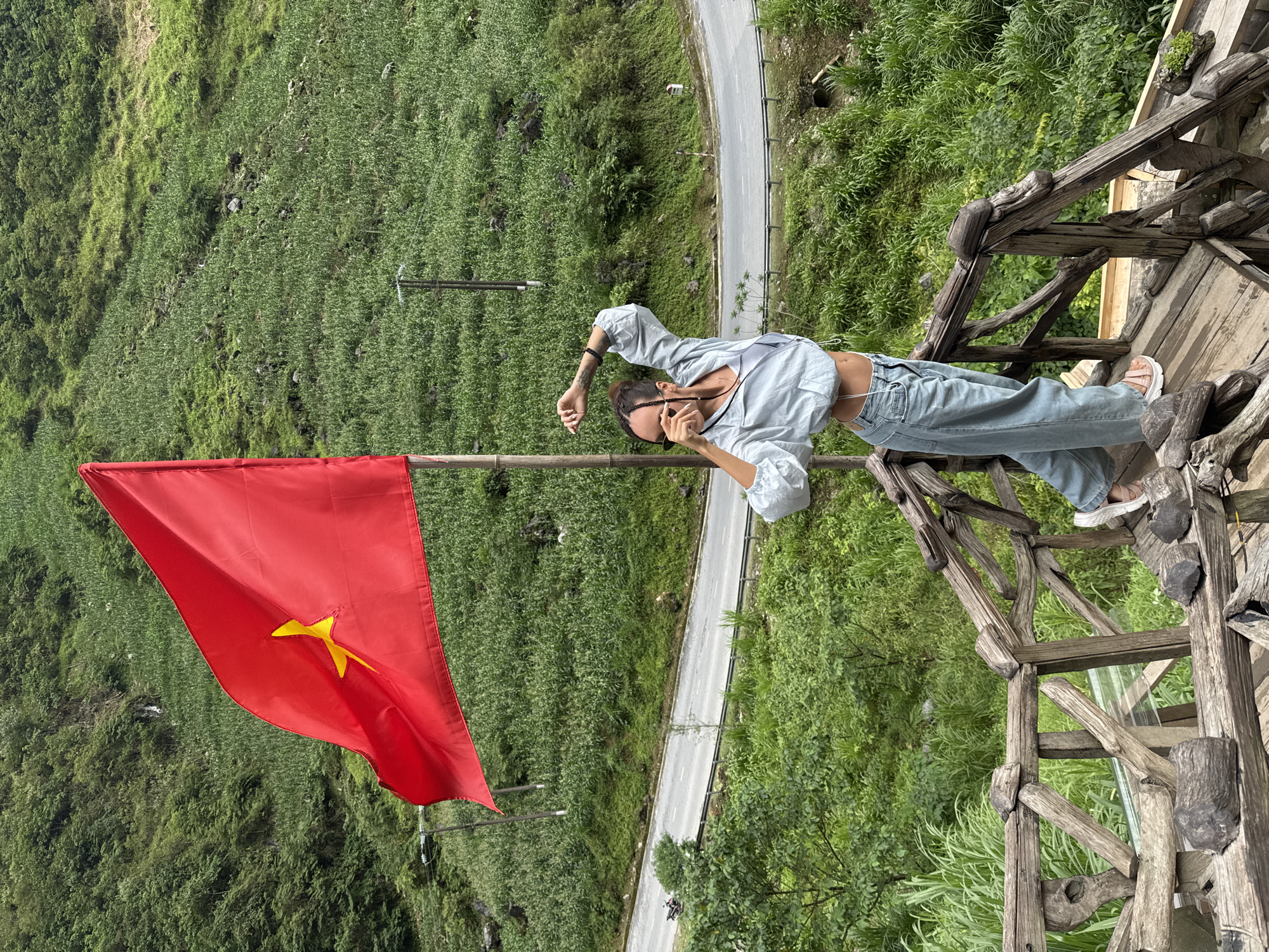 Woman poses near Vietnamese flag in Yên Minh Commune