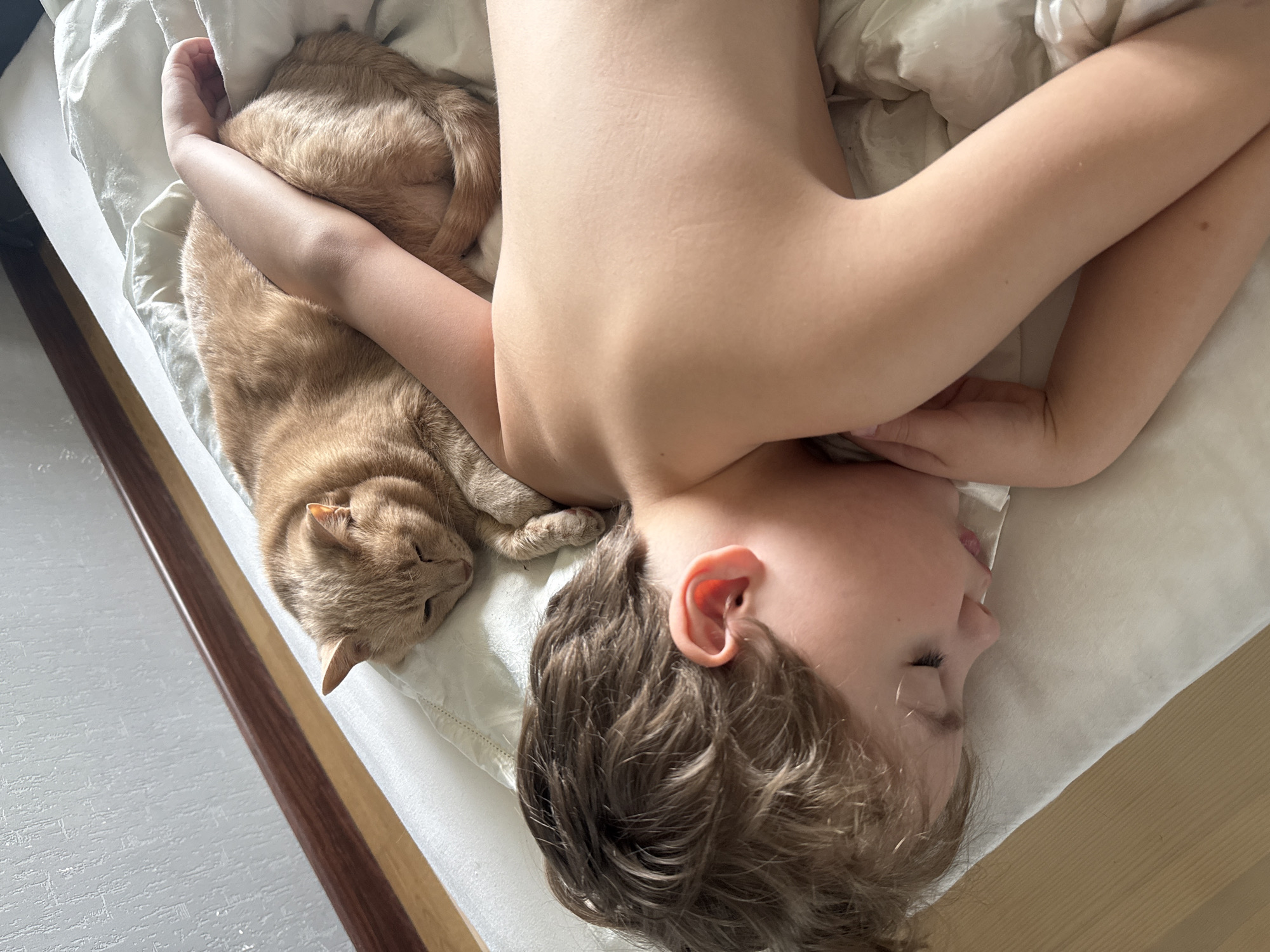 Child and orange cat share bedtime moment in Krasnoyarsk