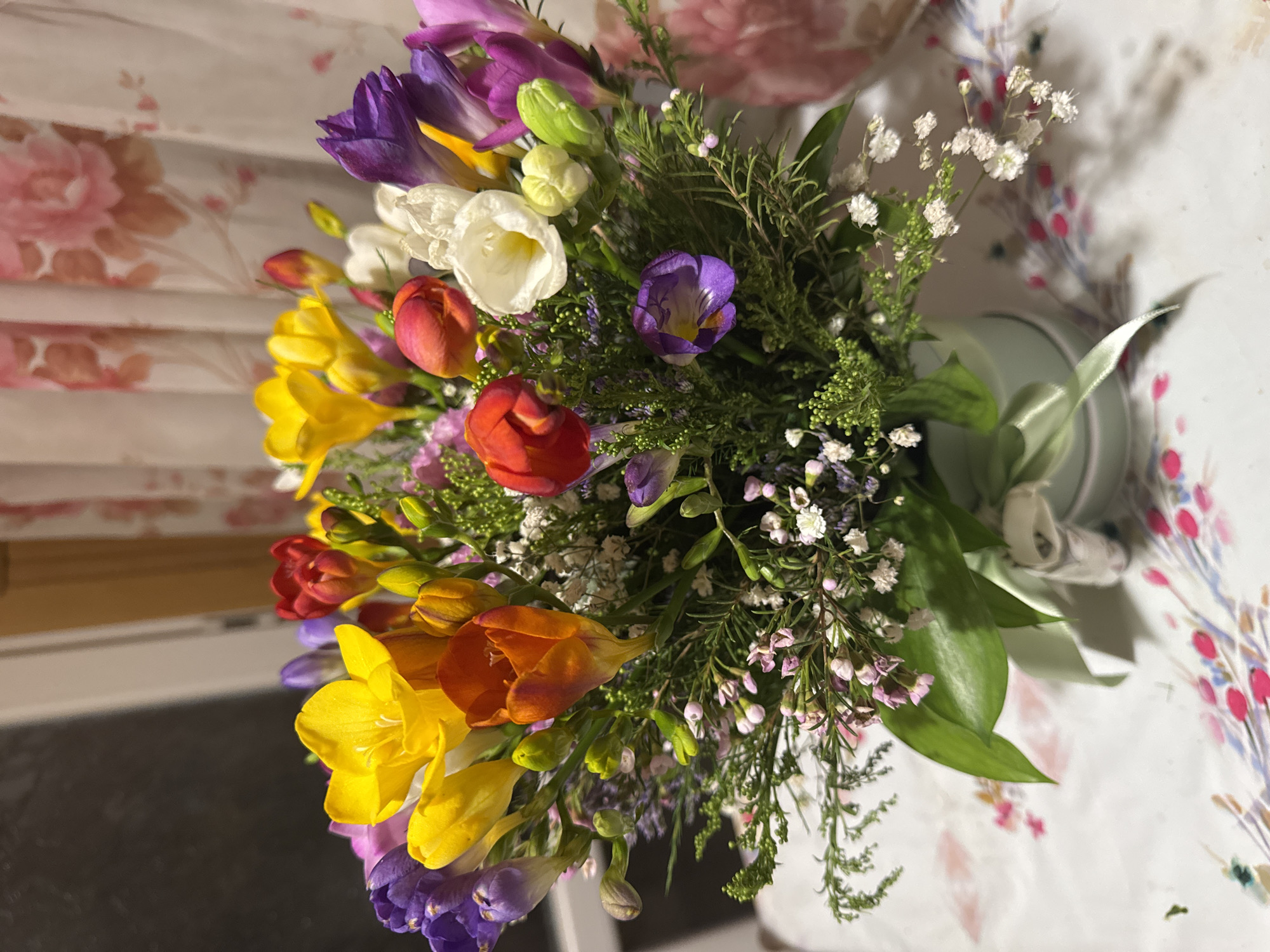 Colorful freesia bouquet arranged in light green vase in Sofia