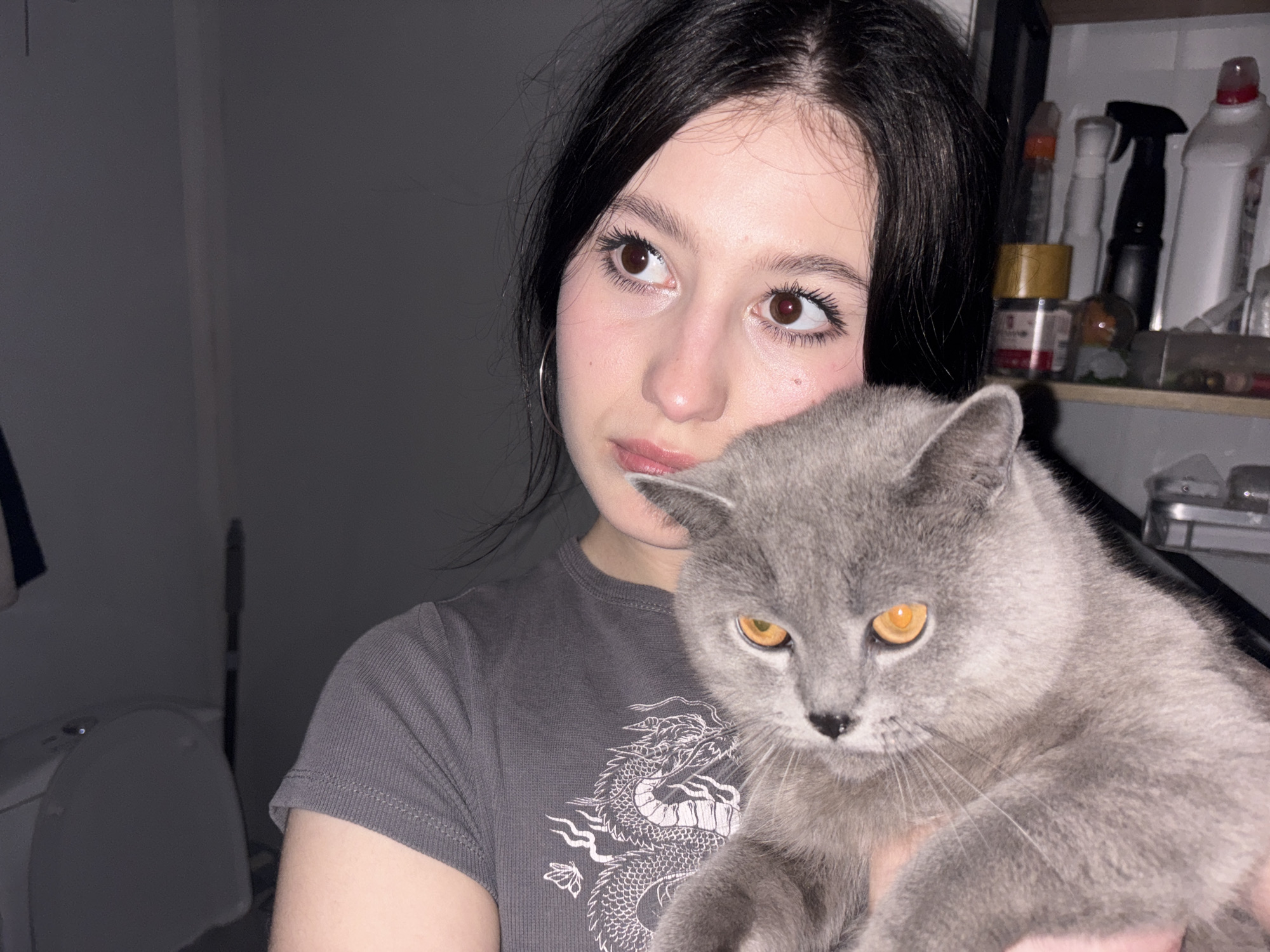 Woman holds gray cat indoors in Russian village