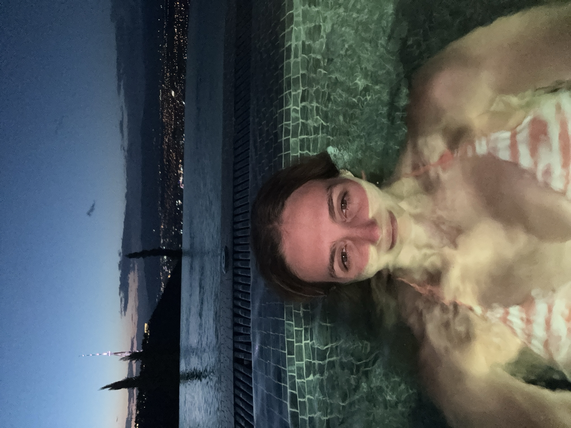 Rooftop pool evening with Tbilisi skyline at dusk