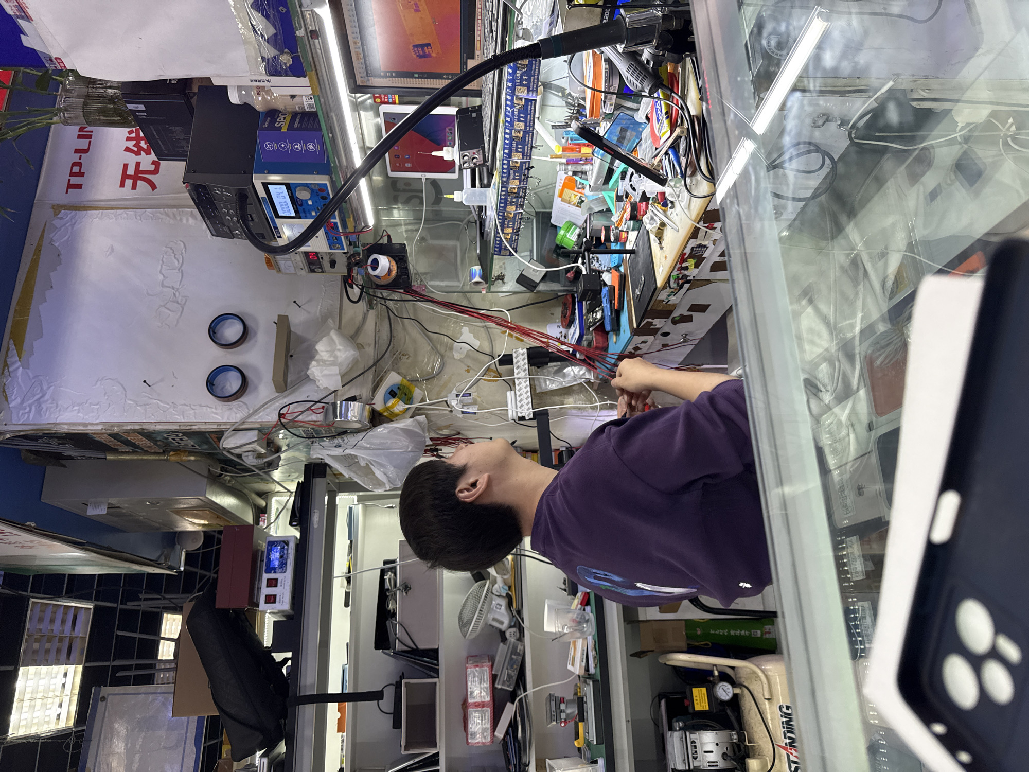 Technician works in cluttered electronics repair shop, Haidian District