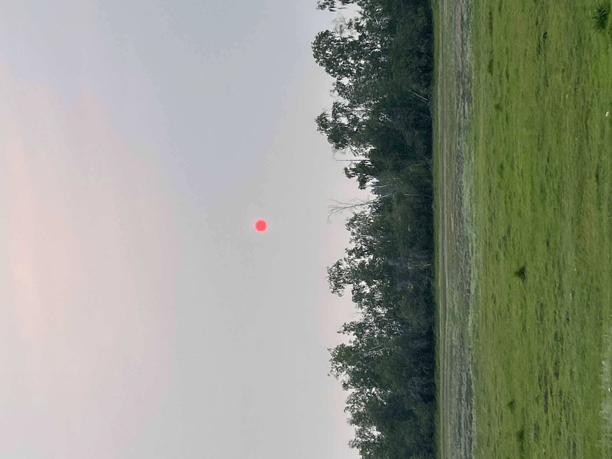 Red sun glows through heavy smoke haze over rural Siberia