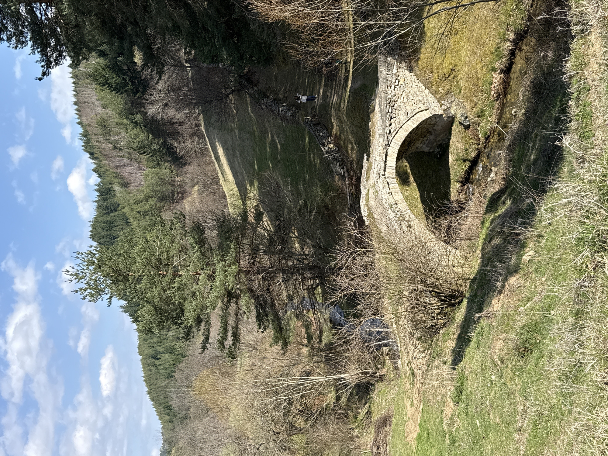 Person crosses historic stone bridge in rural Zagrajden, Bulgaria