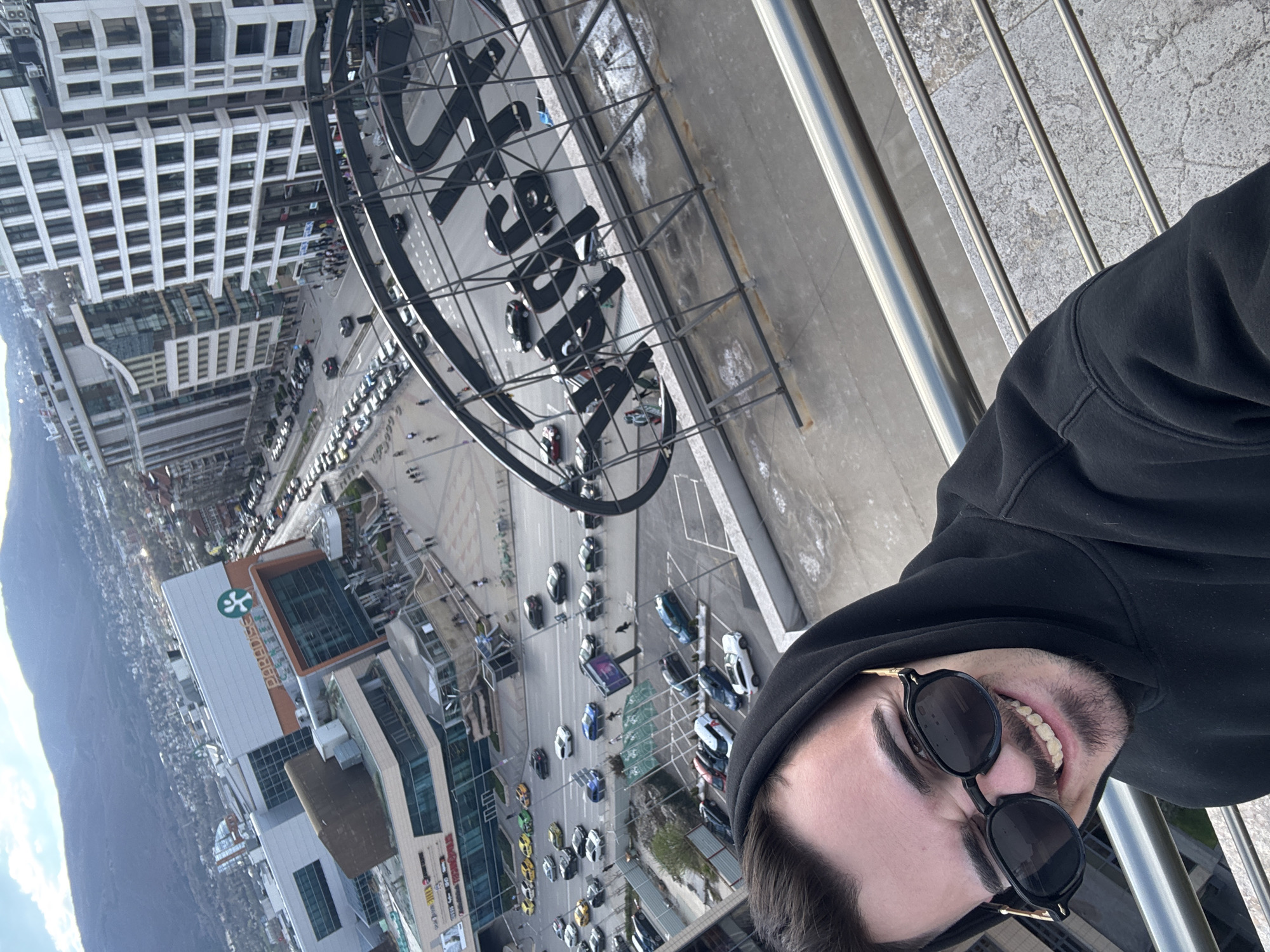 Man takes rooftop selfies overlooking Sofia cityscape and Vitosha Mountain