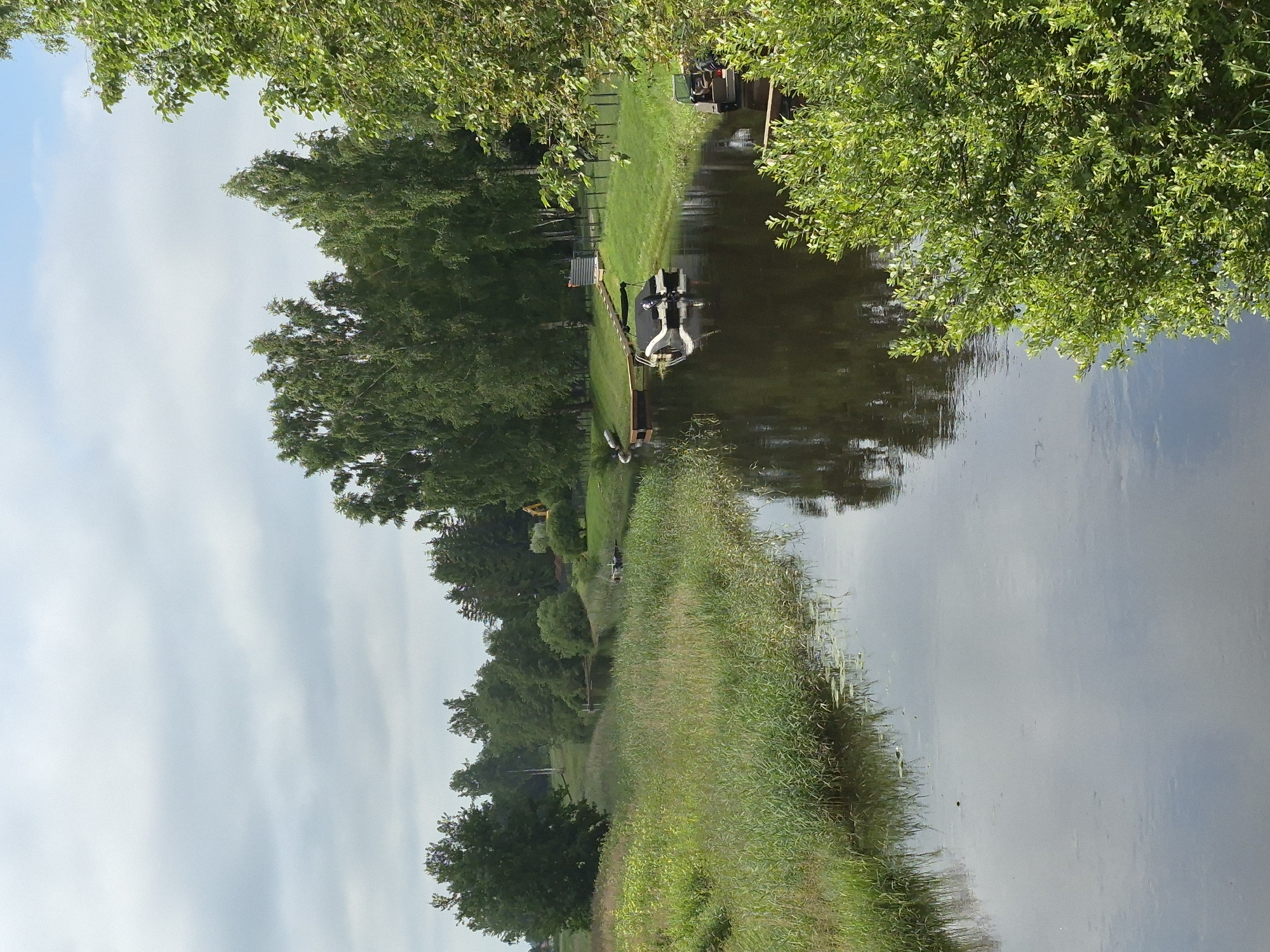 A calm, tree-lined canal on a cloudy morning
