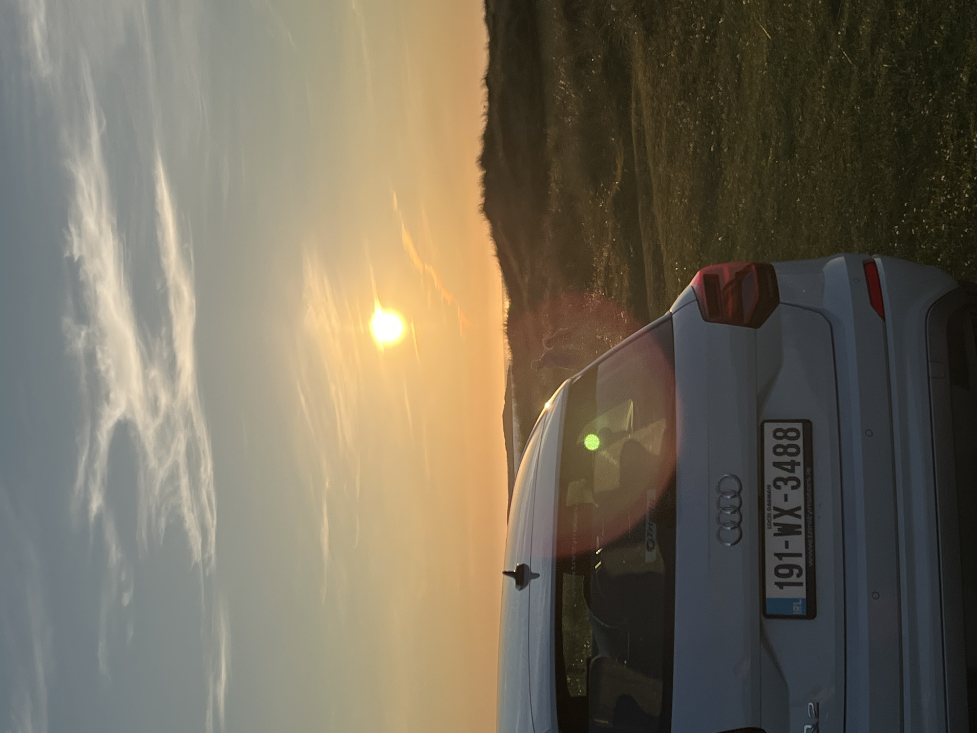 White Audi parked by Irish sand dunes at golden hour