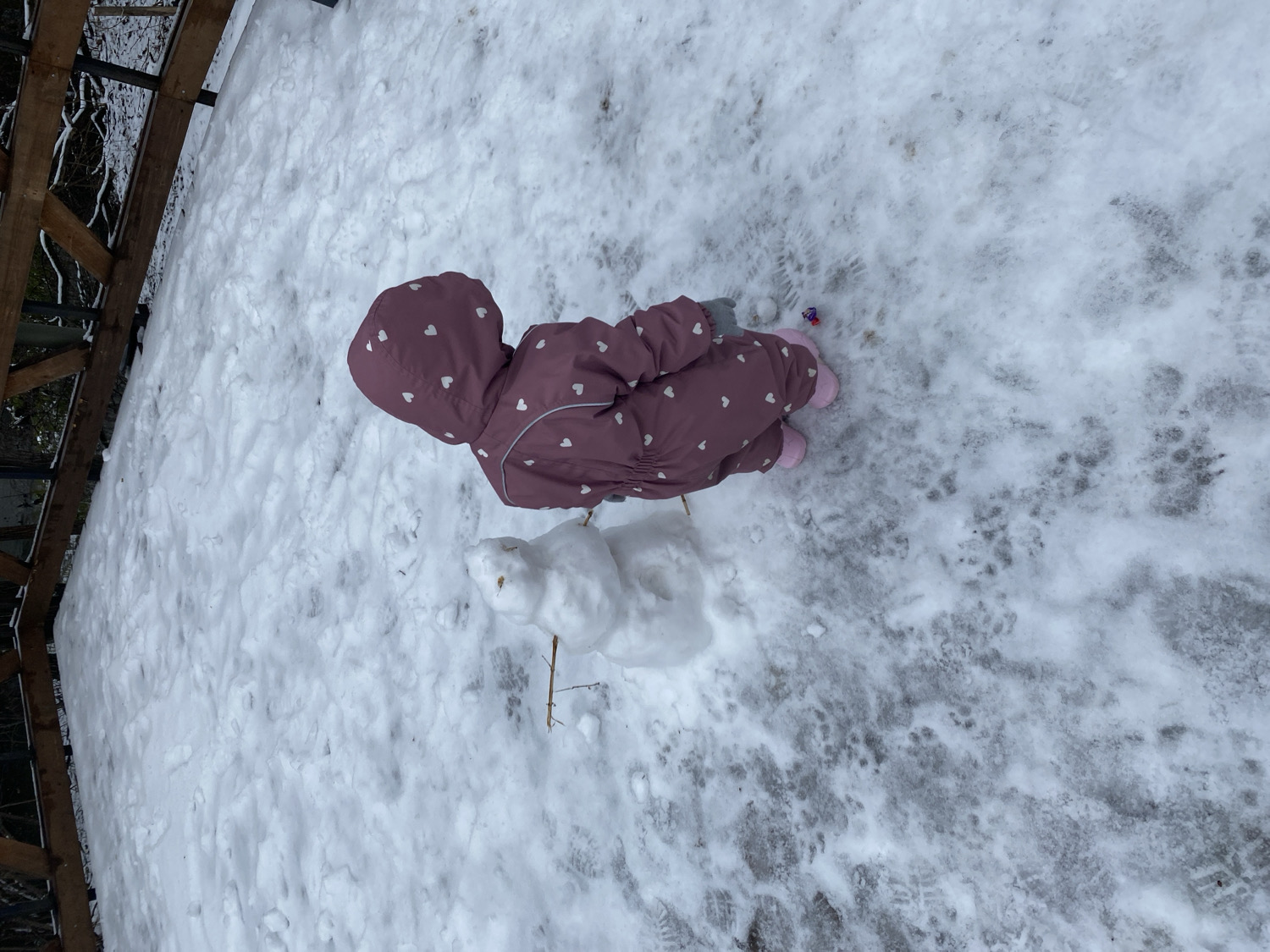 Child plays in snow wearing pink snowsuit in Perm