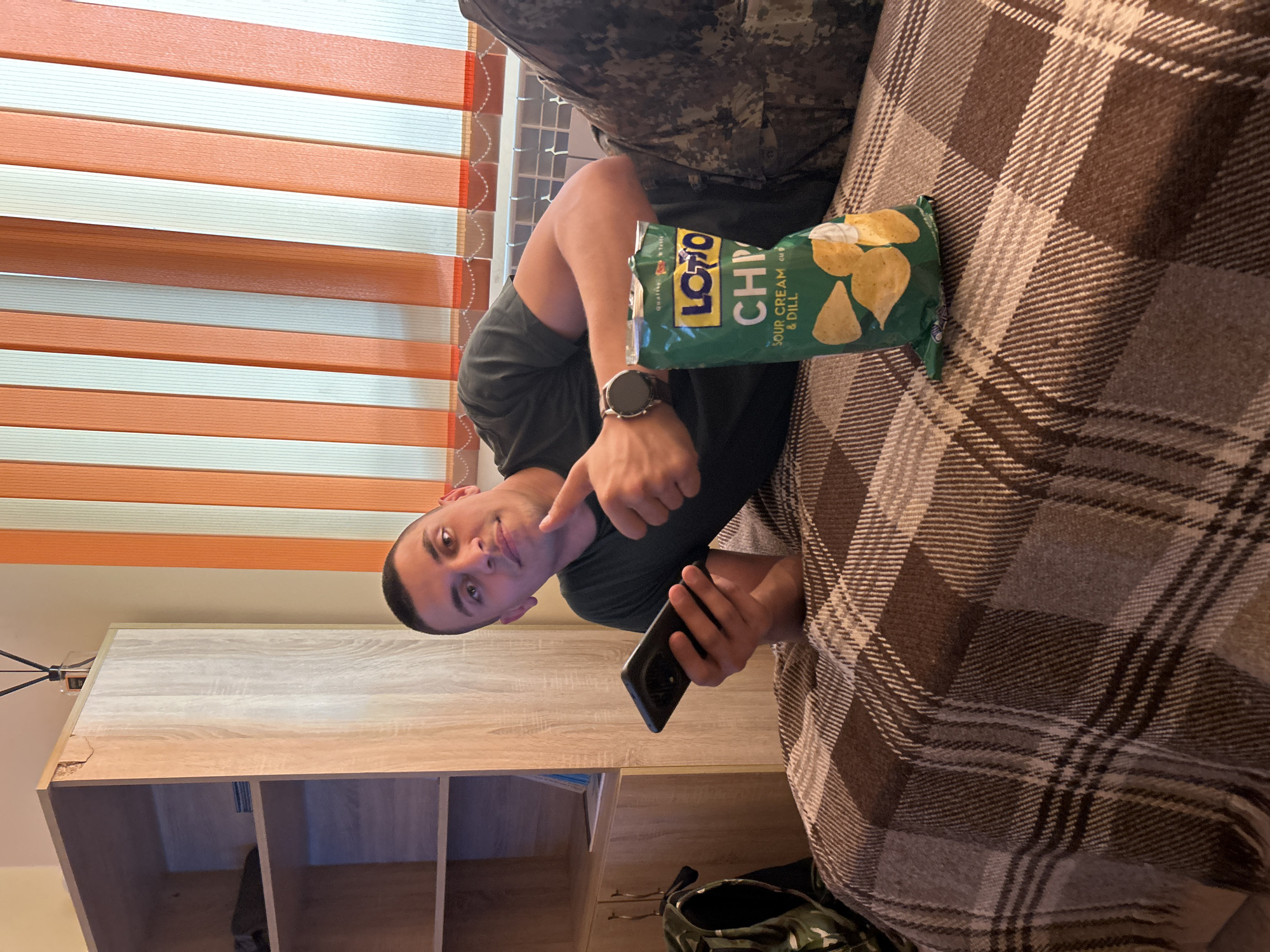 Man with smartphone points while sitting indoors in Shumen