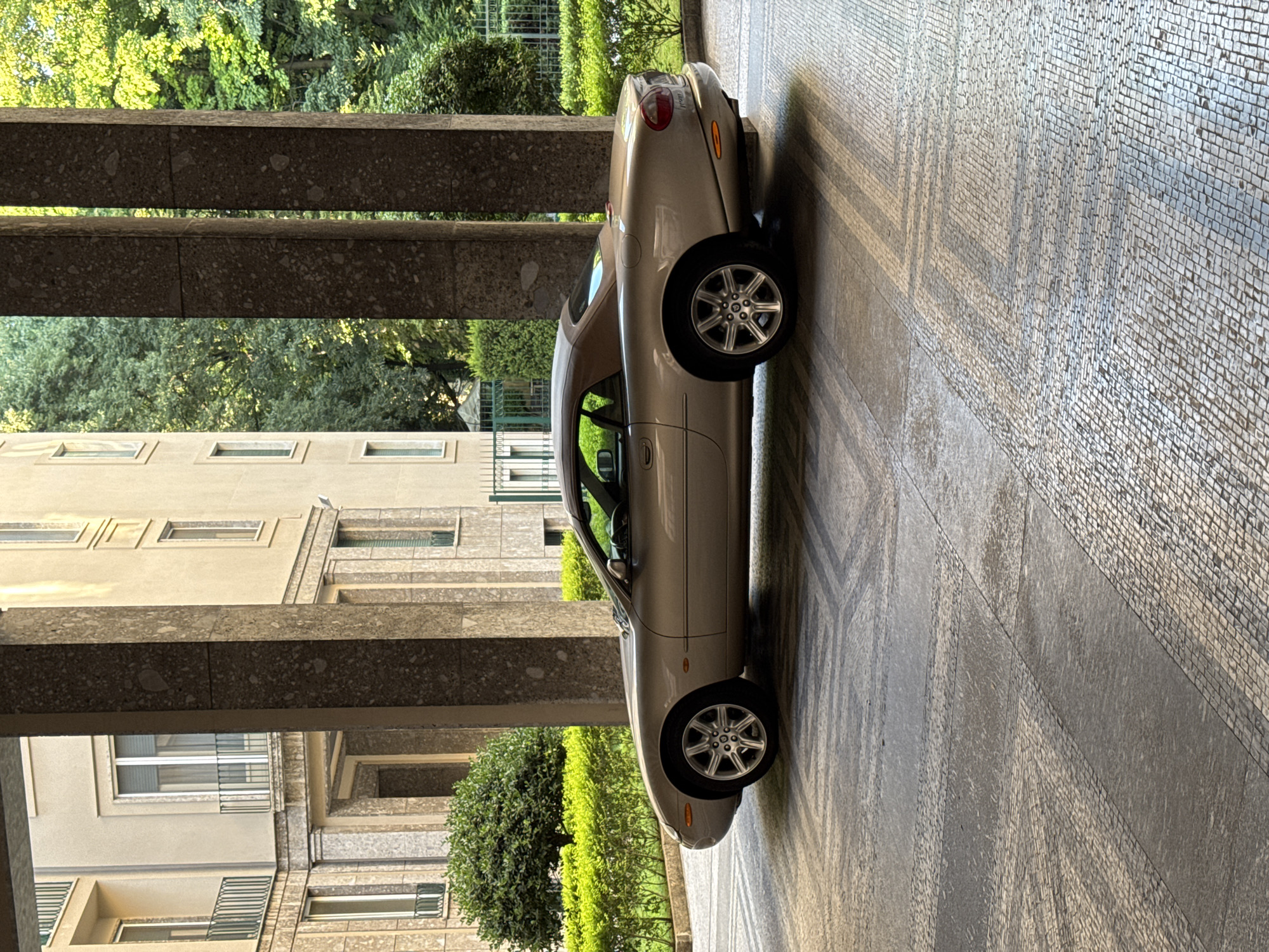Silver Jaguar XK8 parked under Milan portico