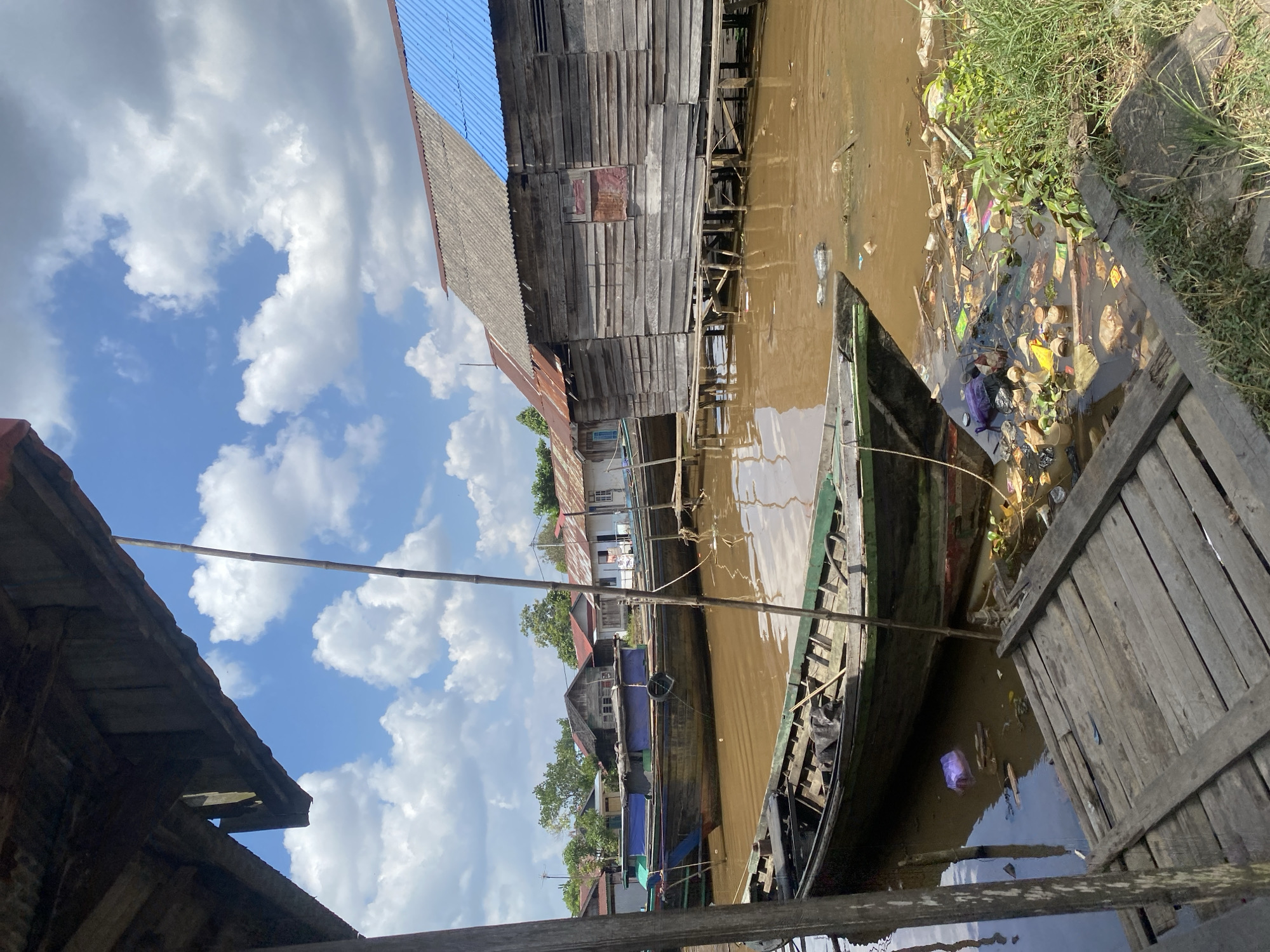Stilt houses and wooden boats along a muddy Borneo riverbank
