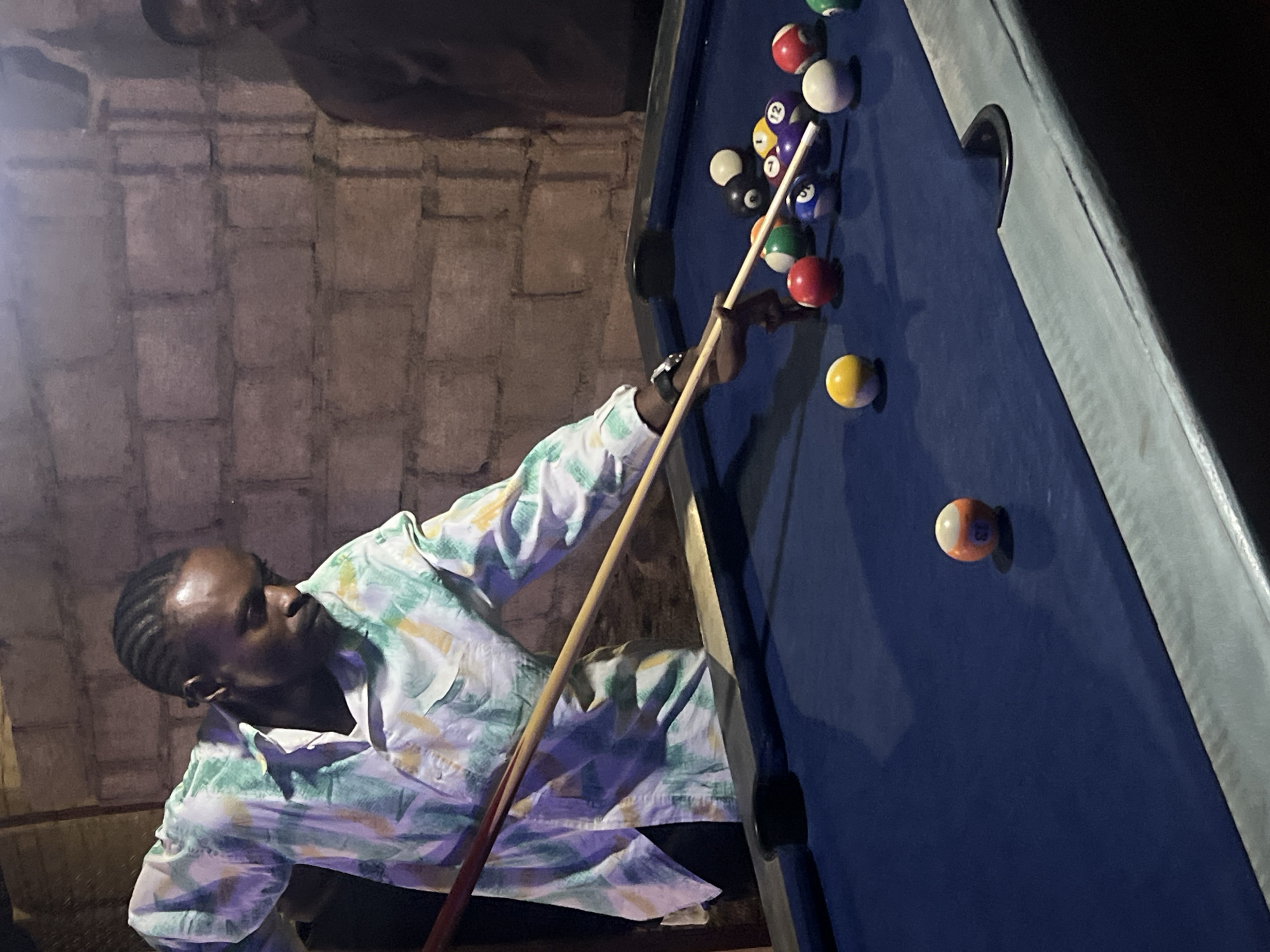 Man plays billiards at dimly lit venue in Nigeria