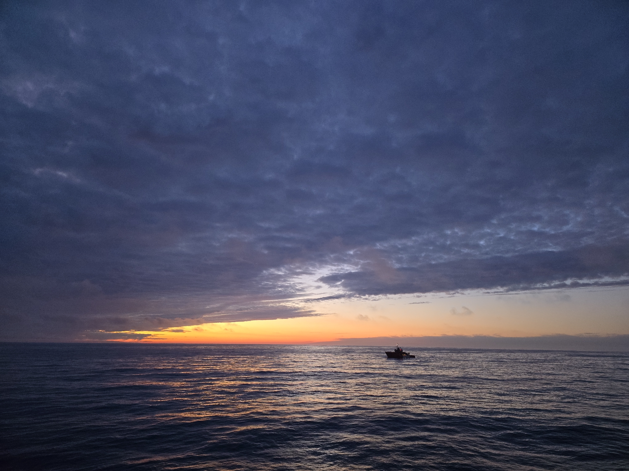 Boat observed on ocean during dramatic sunset