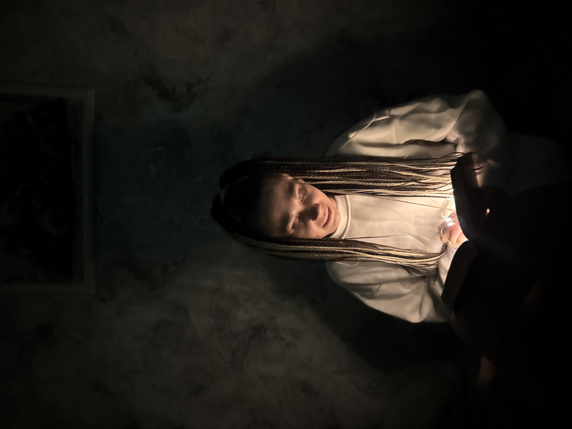 Woman with braided hair observed in dimly lit indoor space