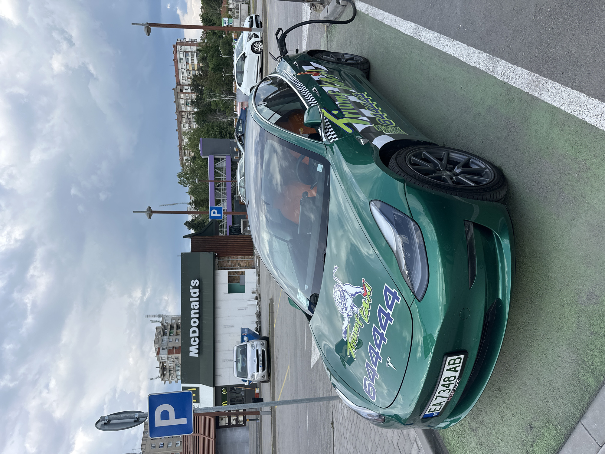 Green Tesla taxi charges outside McDonald's in Bulgarian city