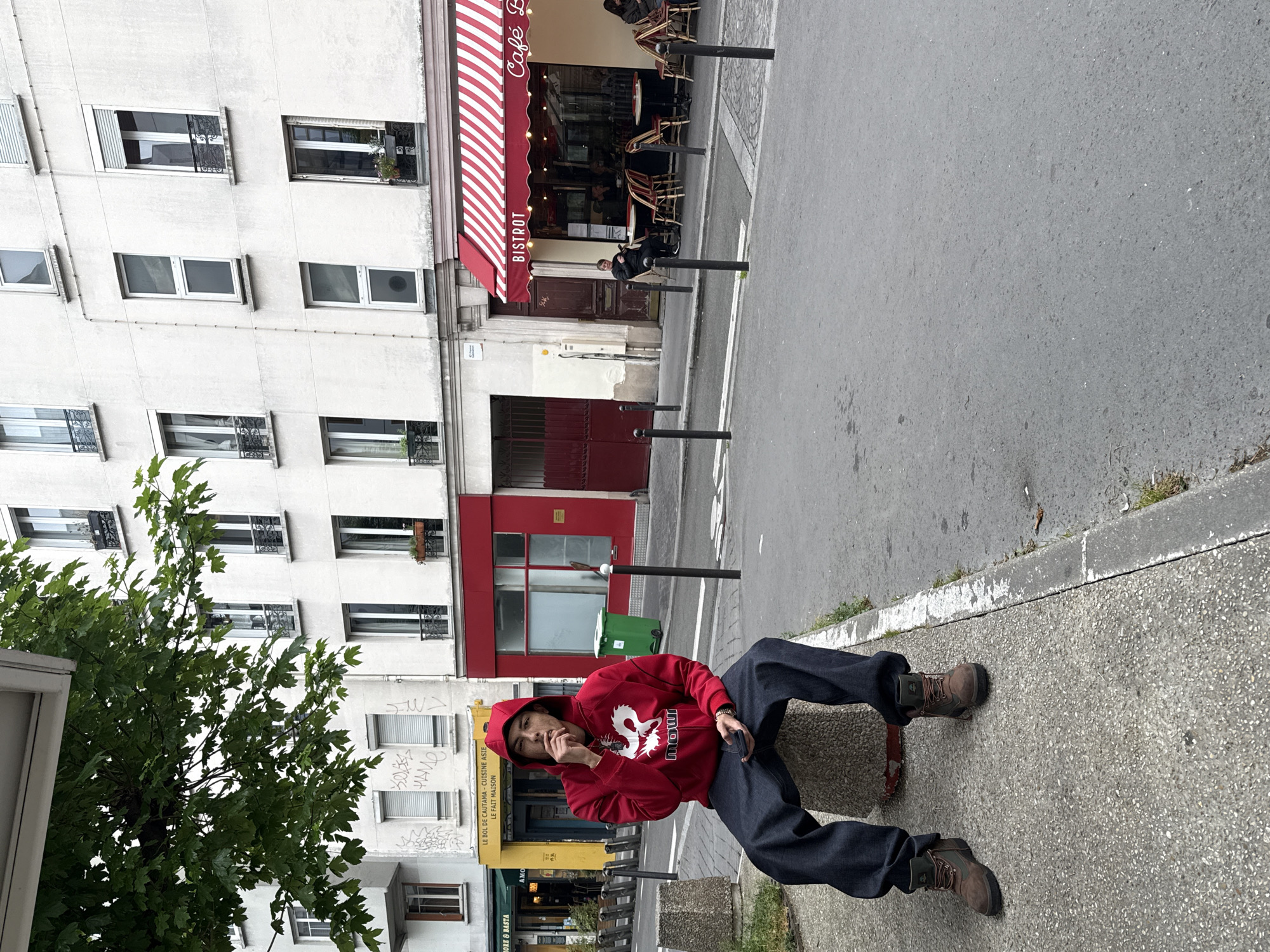 Person in red hoodie sits on concrete structure in Paris