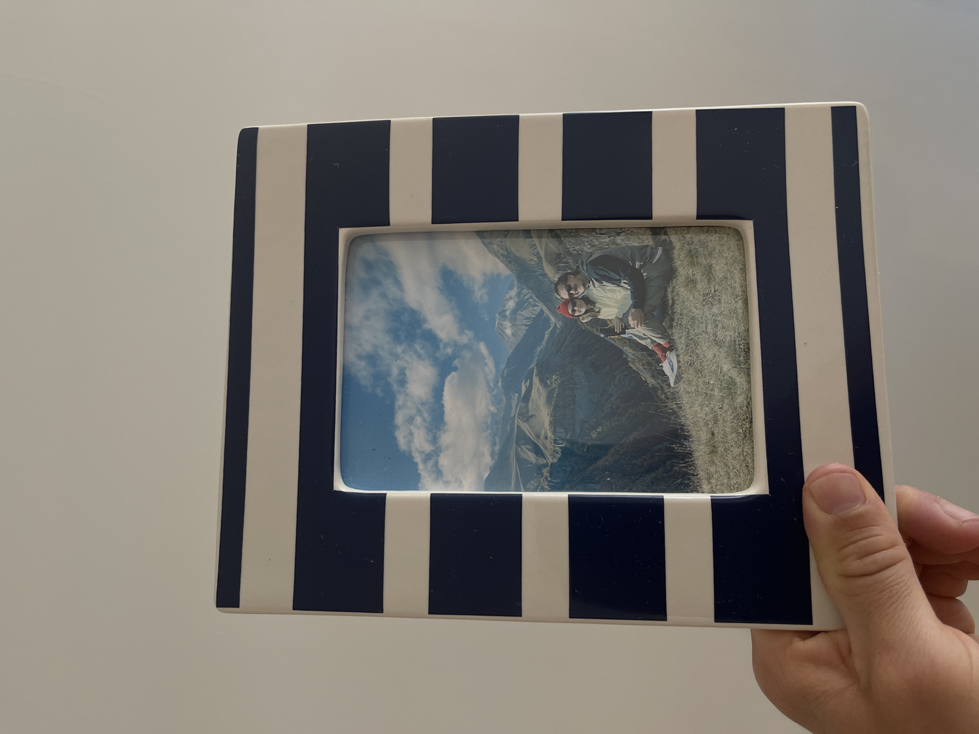 Person holds framed photo of couple in mountains