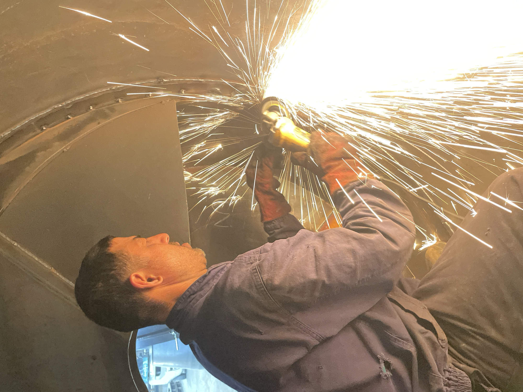 Worker operates angle grinder inside metal structure in Montenegro