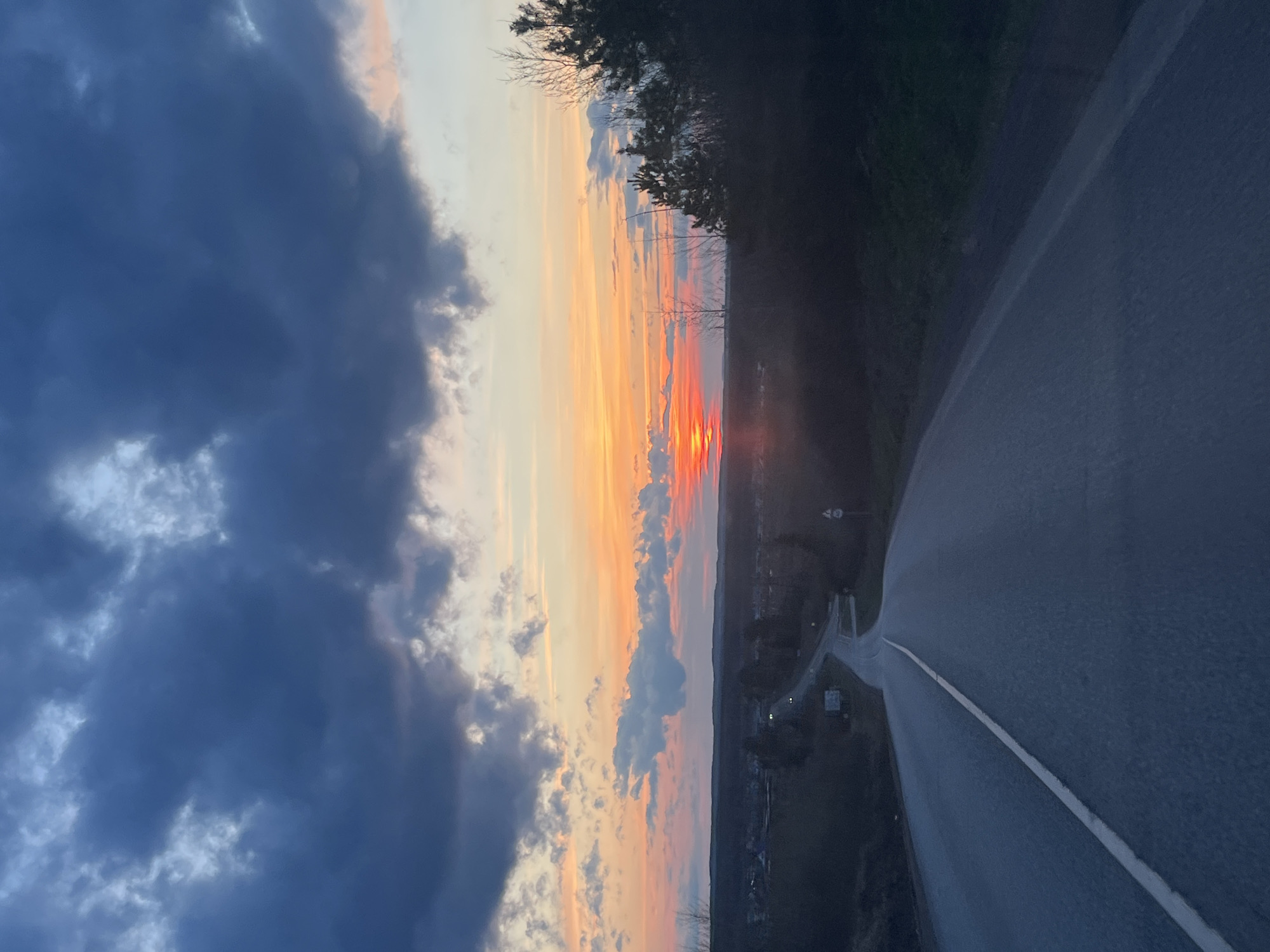 Sunset road scene contrasts storm clouds with vibrant skies