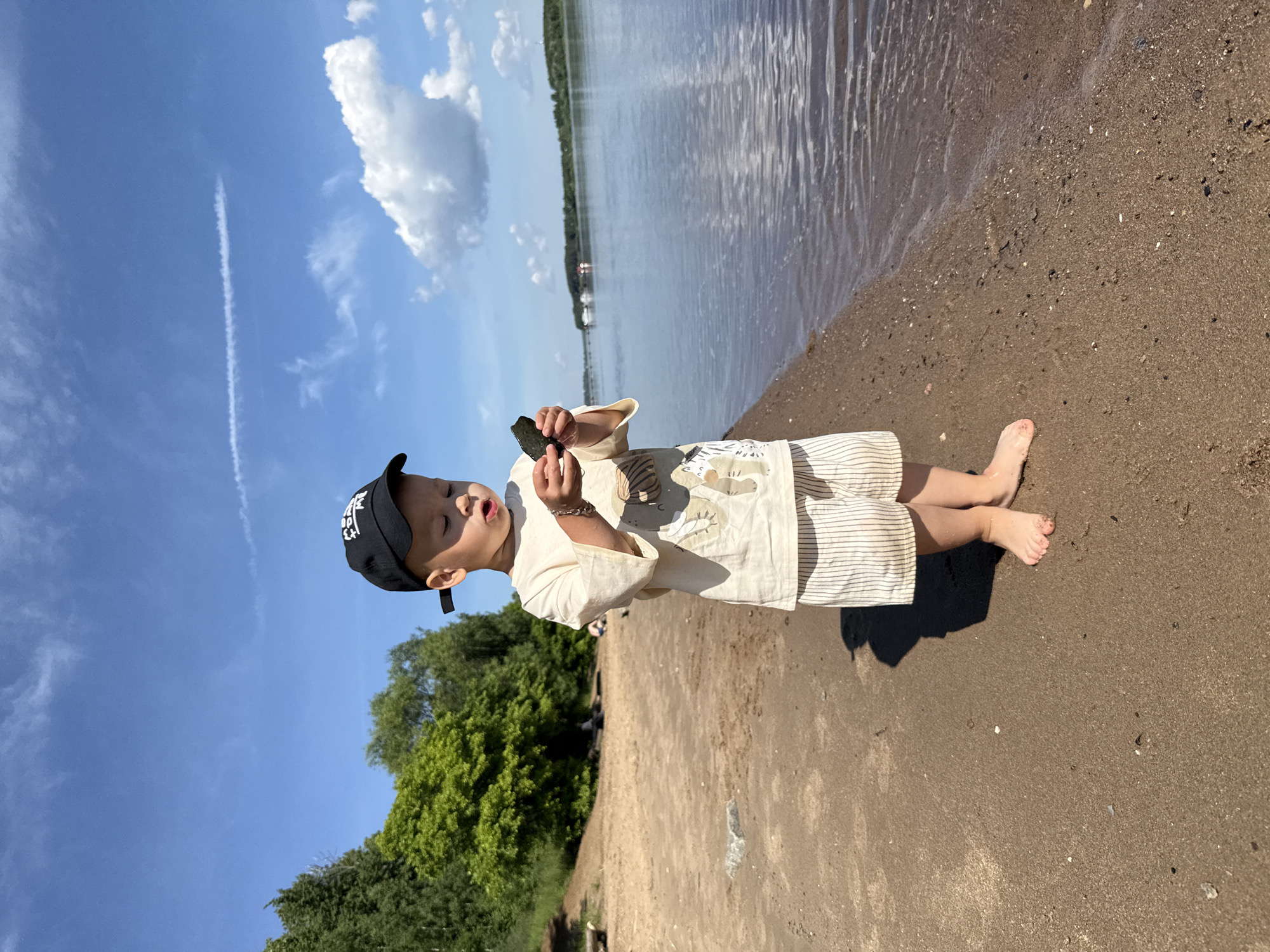 Boy with dark object stands on beach