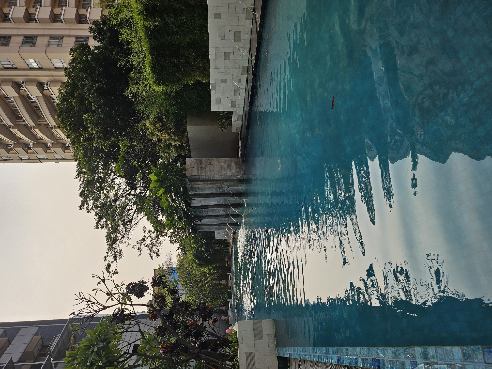 Turquoise pool reflects Jakarta's modern skyline on a quiet morning