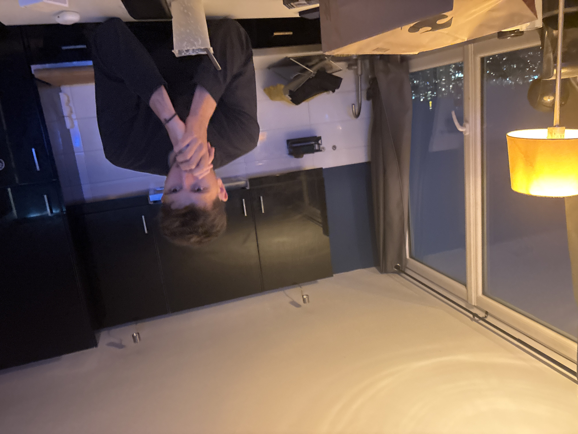 Man stands in modern Parisian kitchen with hands near face