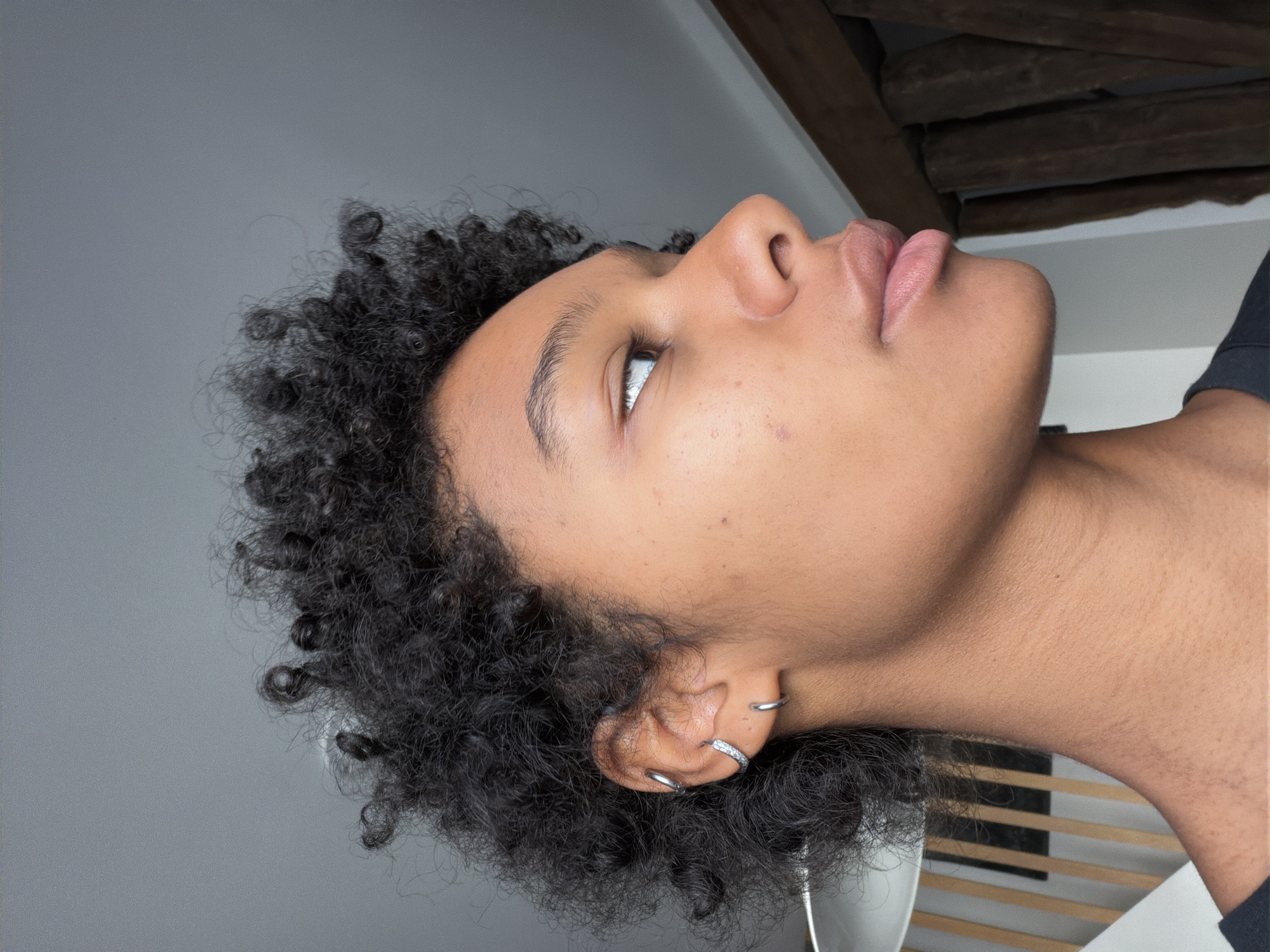 Close-up profile with curly hair and stone-accented hoop earrings, Paris