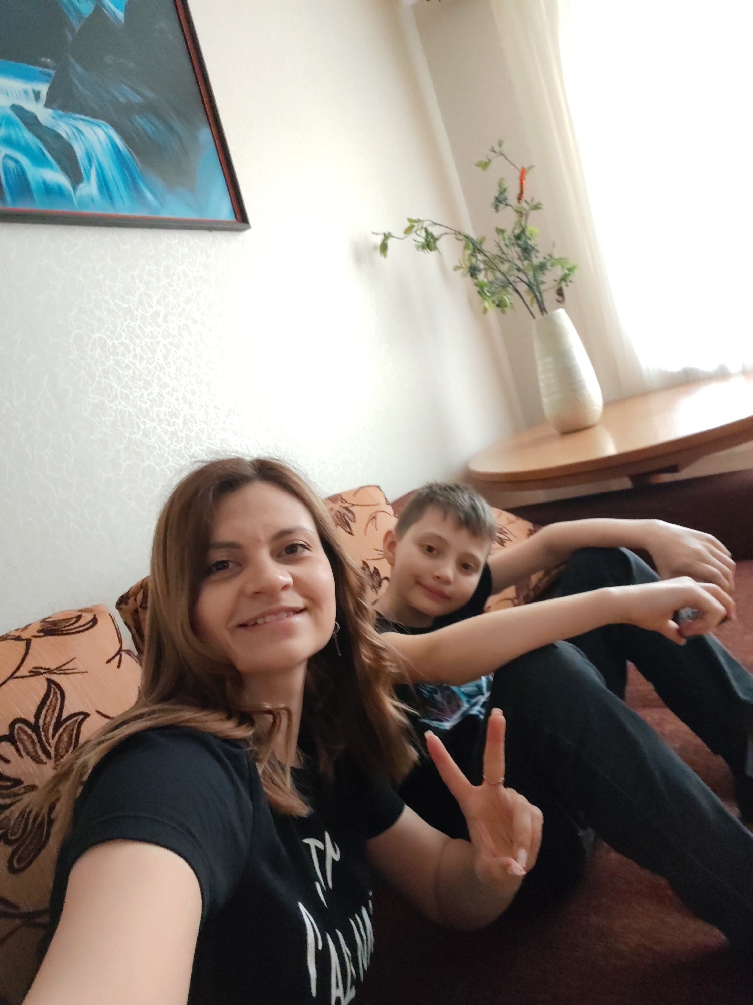 Woman and boy photographed on couch, peace sign gesture