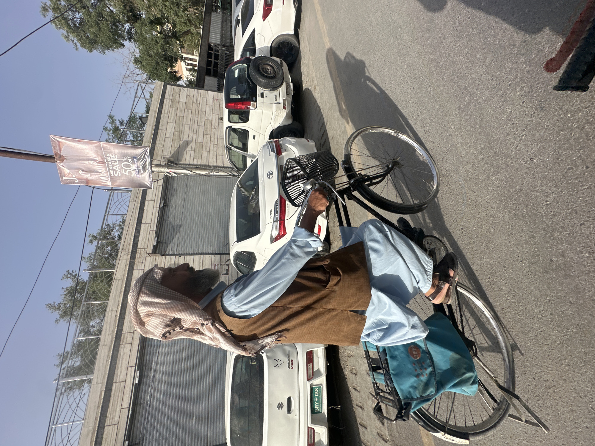 Elderly man cycles through busy Quetta street in traditional dress