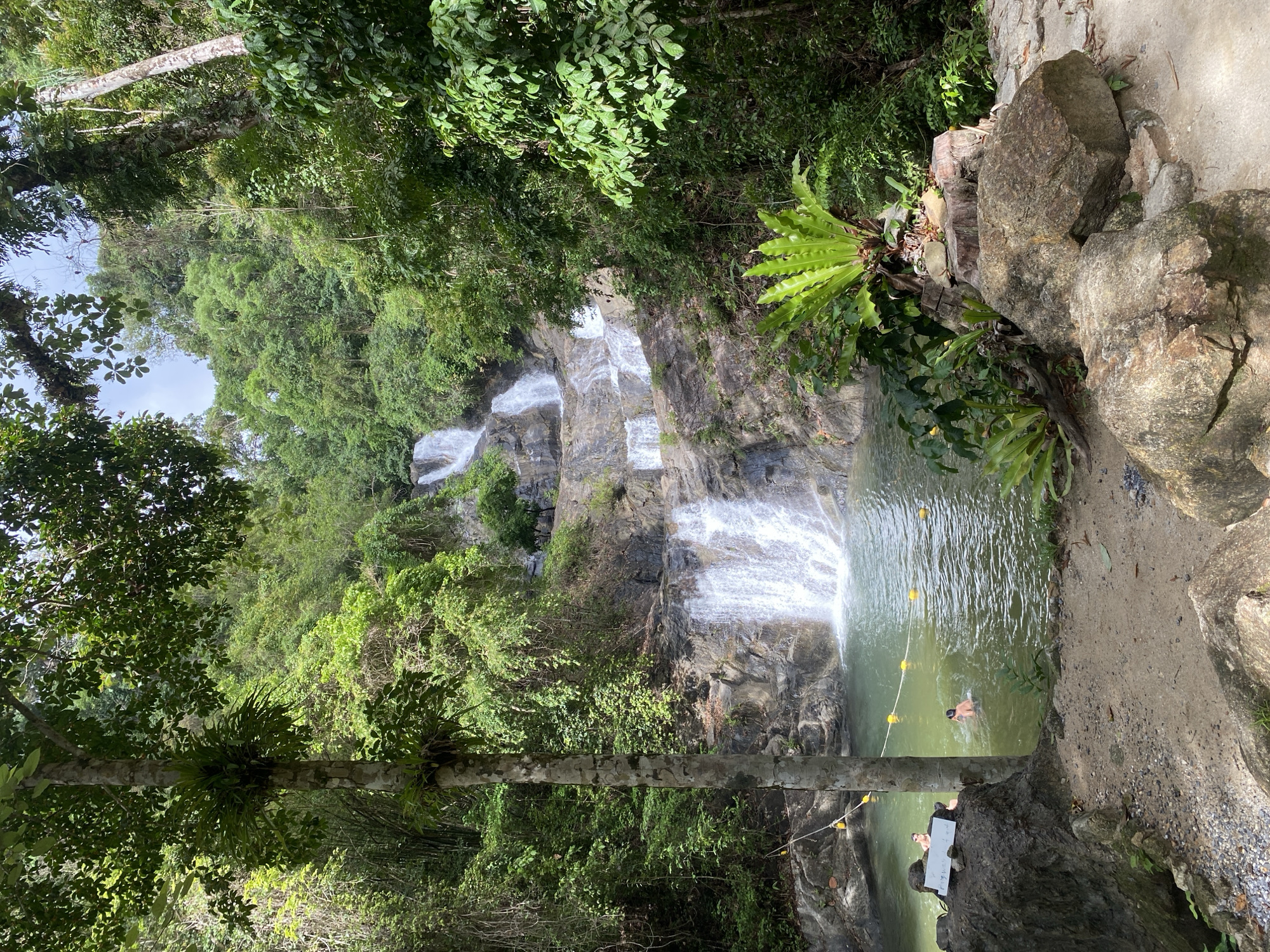 Tourist visits Thai Mueang waterfall attraction, documents nature experience