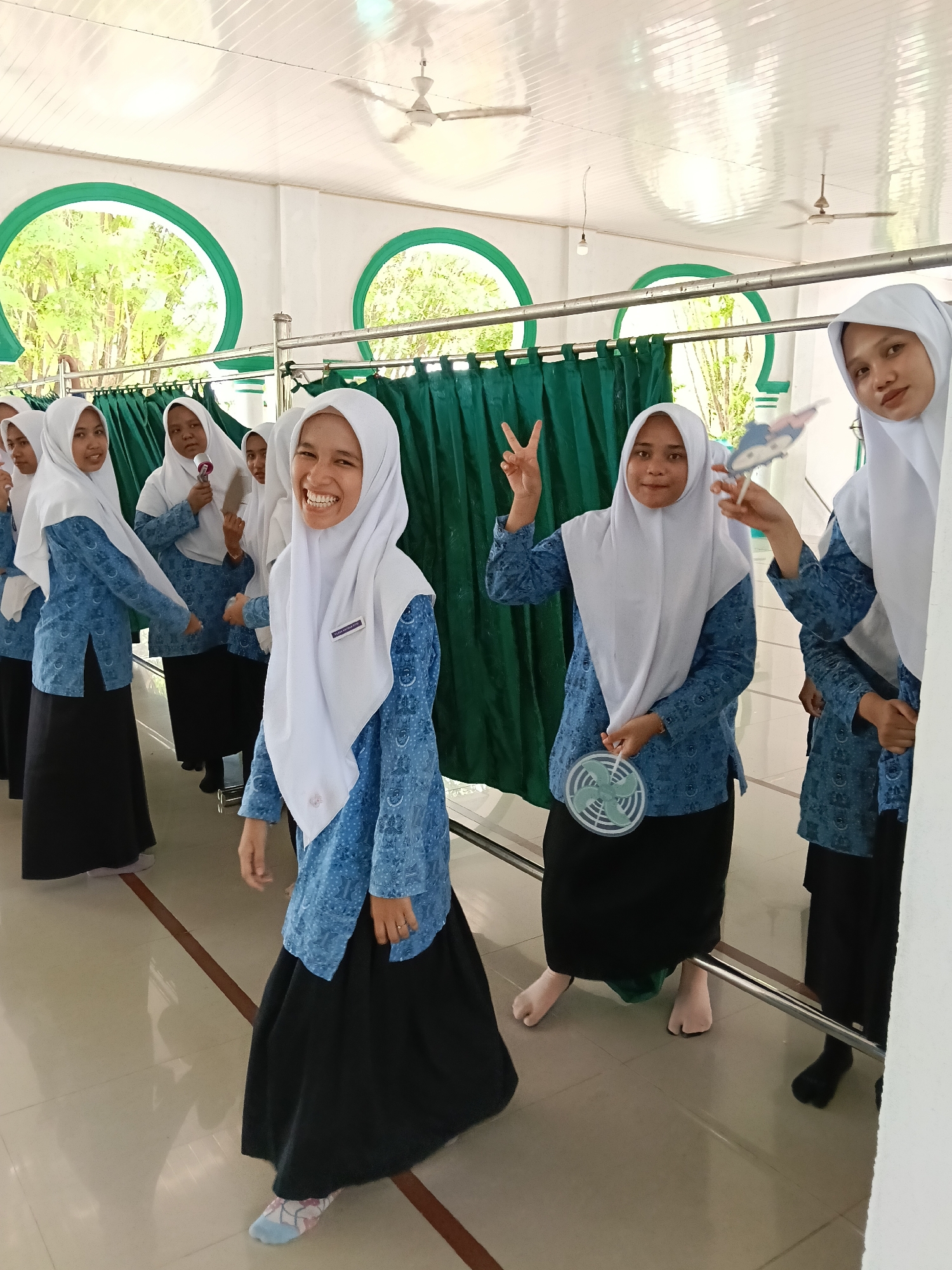 Students and teacher pose in Indonesian school hallway