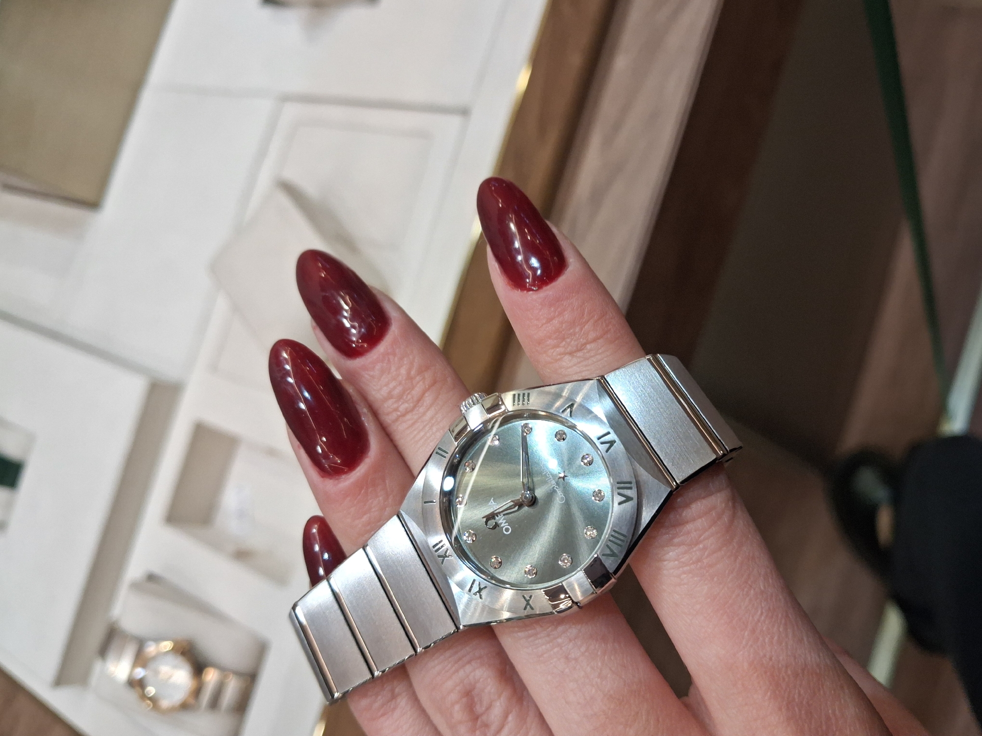 Silver watch with diamond markers spotted on burgundy-nailed hand