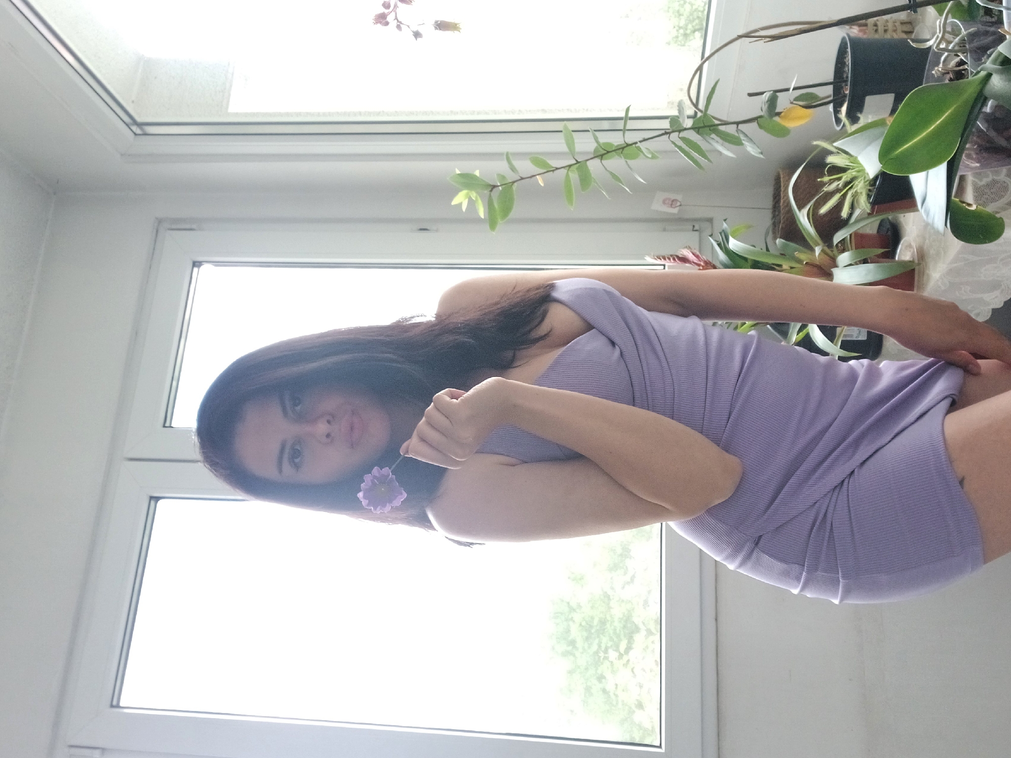 Woman poses with purple flower in Sofia apartment