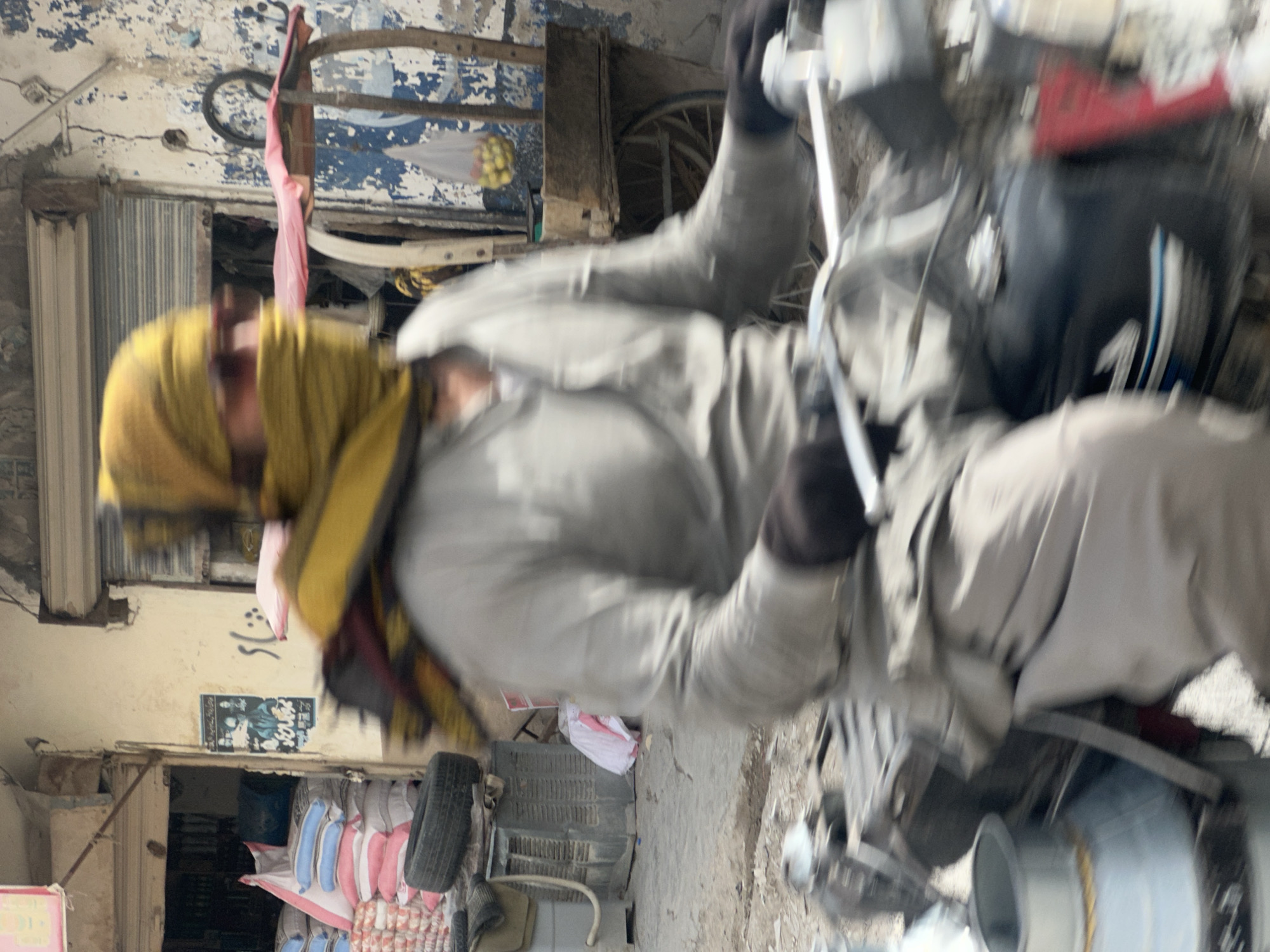 Motorcycle rider navigating Quetta streets, masked and sunglassed.