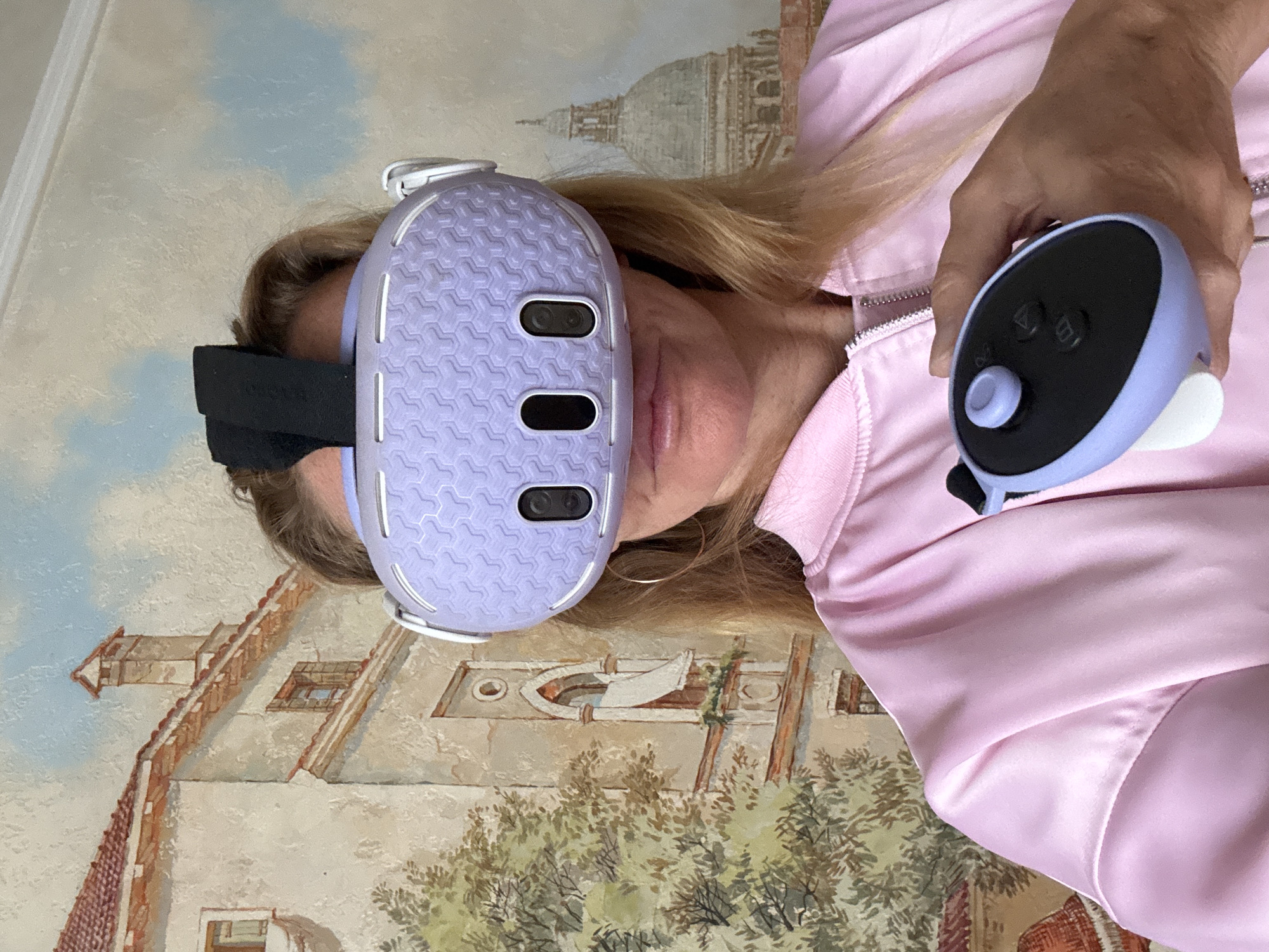 Person holds purple VR headset near building mural in Sinyavino