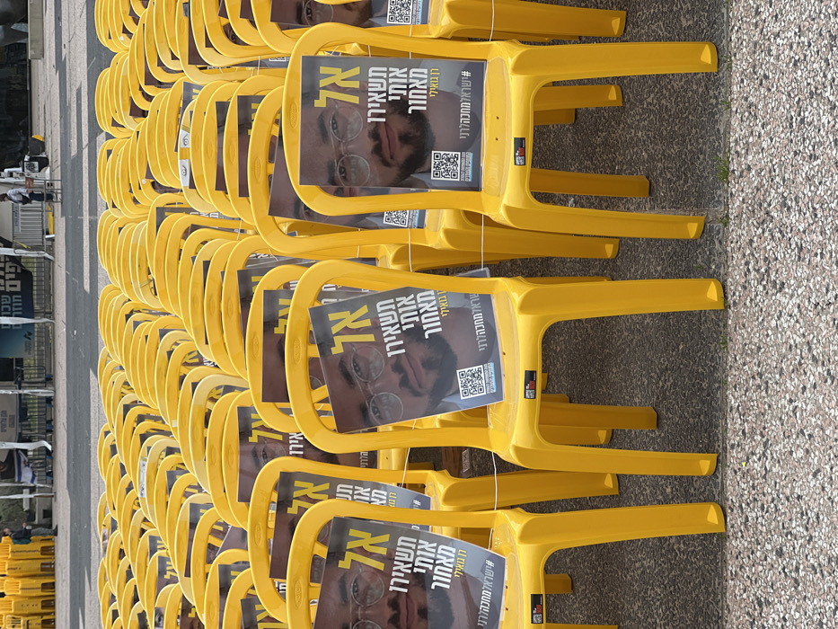 Memorial chairs with portraits displayed alongside Israeli flags in Tel Aviv