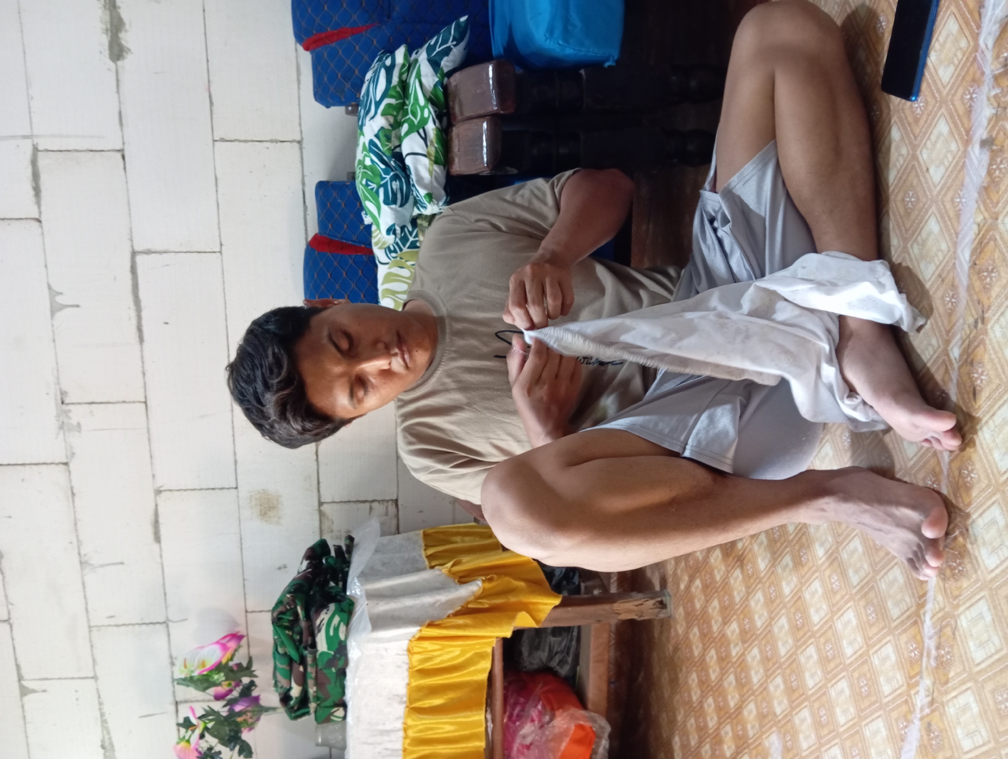 Man rests on wooden bench indoors in Baron, Indonesia