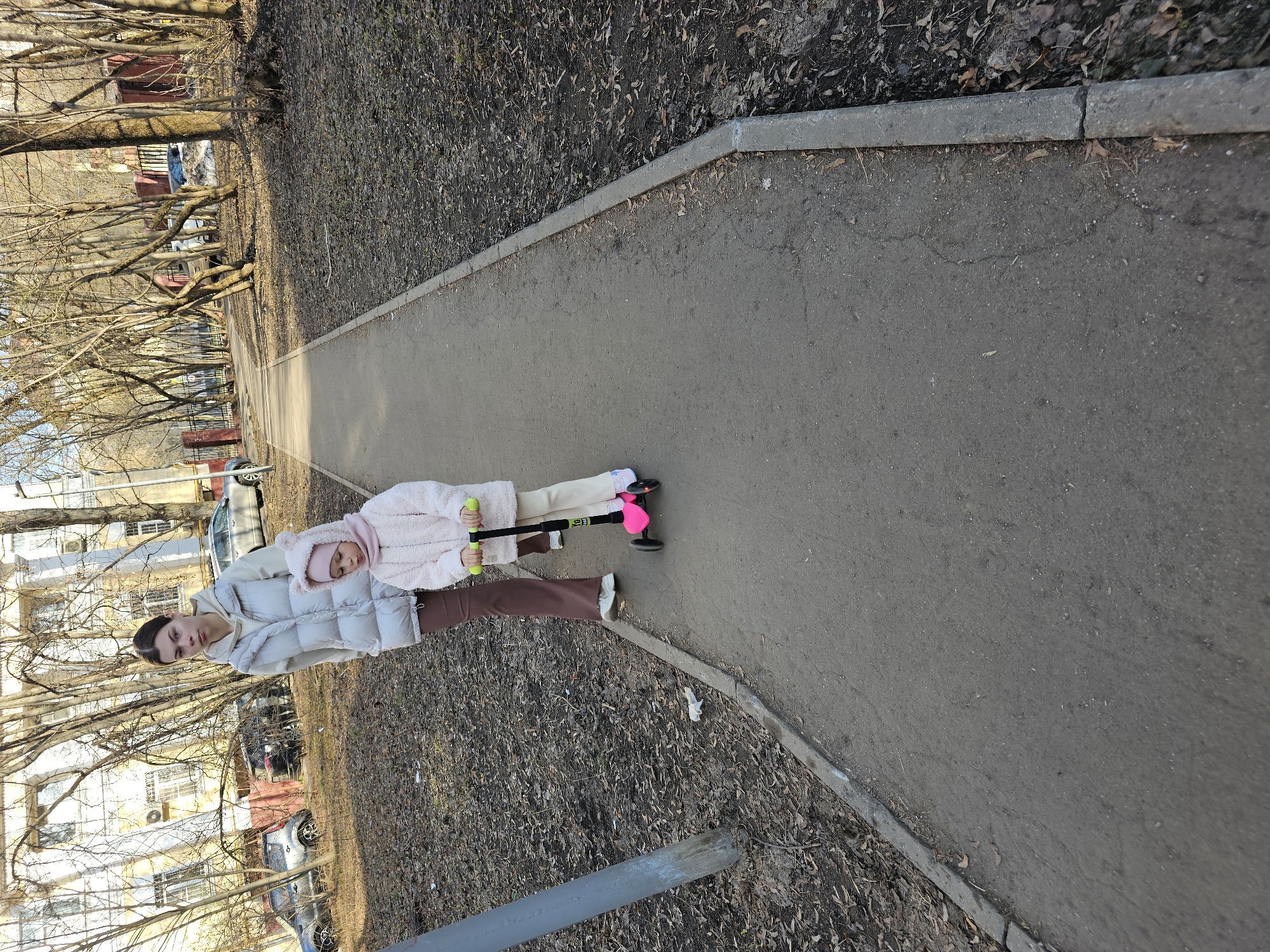 Woman and child walk with scooter on Moscow path