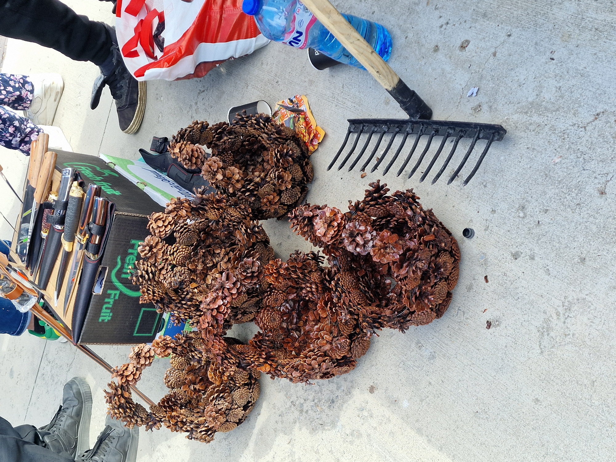 Pine cone wreaths and gardening tools arranged on concrete