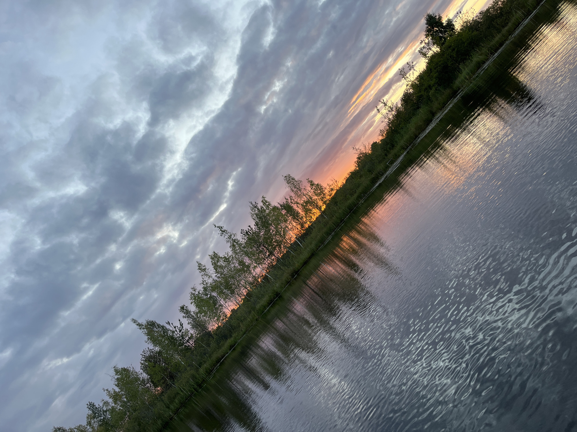 Dusk on a calm Belarusian lake, viewed from a wooden boat