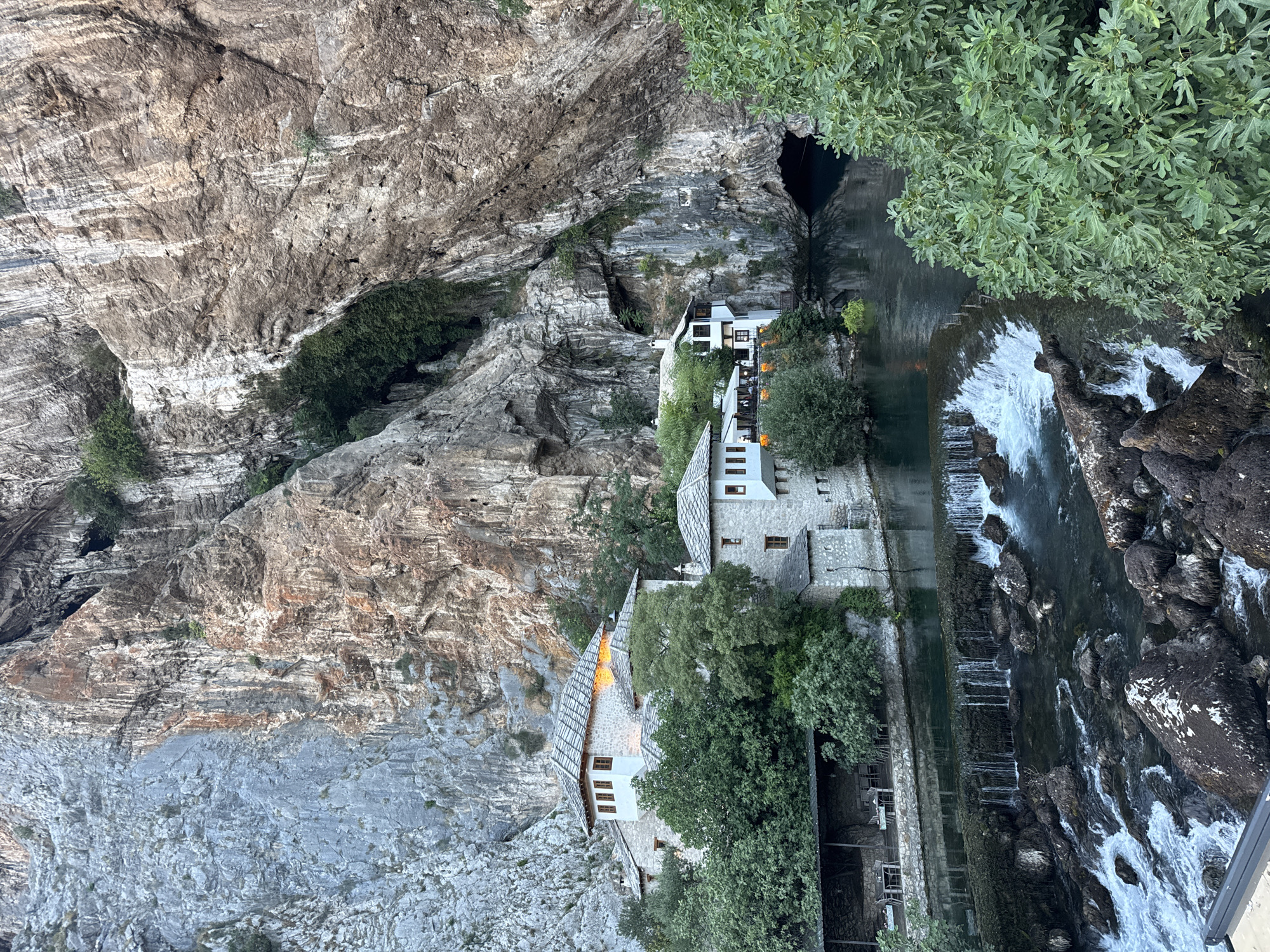 Stone village architecture nestled beneath cliffs in rural Bosnia
