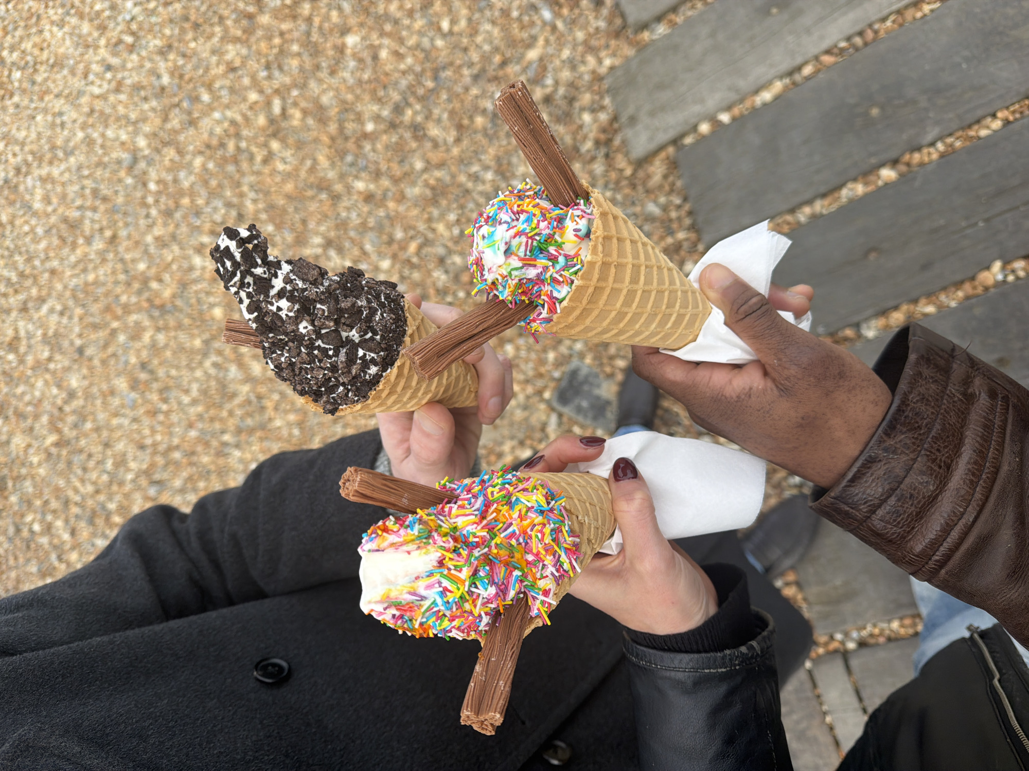 Three people enjoy ice cream cones on Folkestone boardwalk
